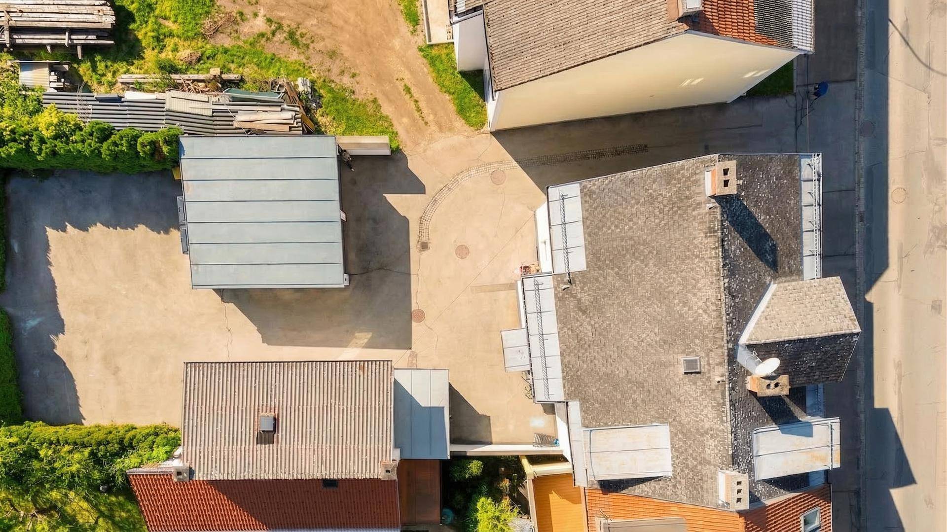 Vogelperspektive von Dächern und umliegenden Gebäuden mit Parkflächen und Wegen in der Nachbarschaft.