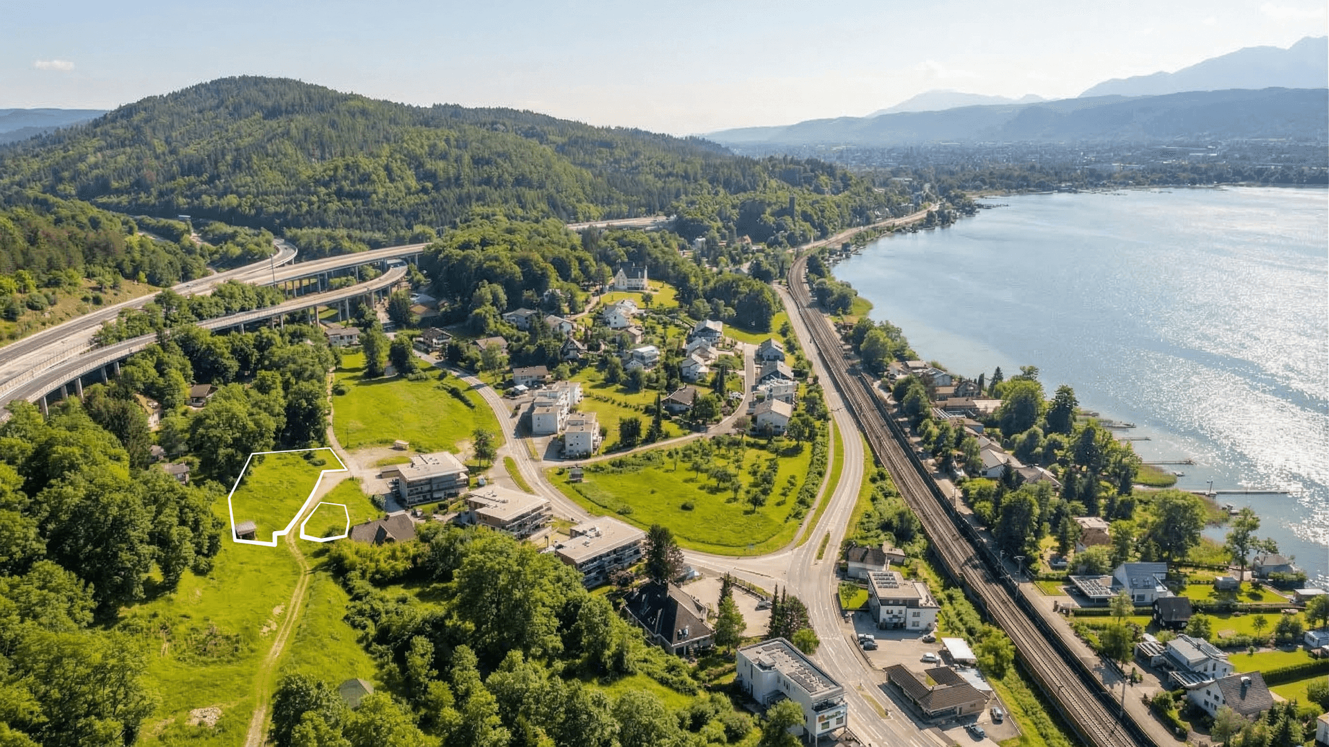 Luftaufnahme der Umgebung mit See, Bergen und der Lage des Grundstücks in der Siedlung.