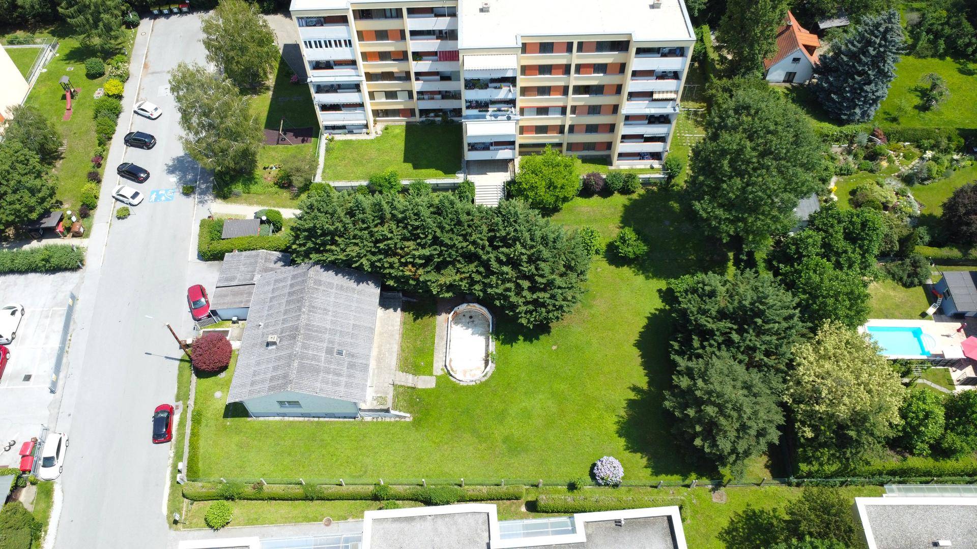 Nähere Luftaufnahme des Anwesens mit Hauptgebäude, Rasenfläche und Baumbestand.