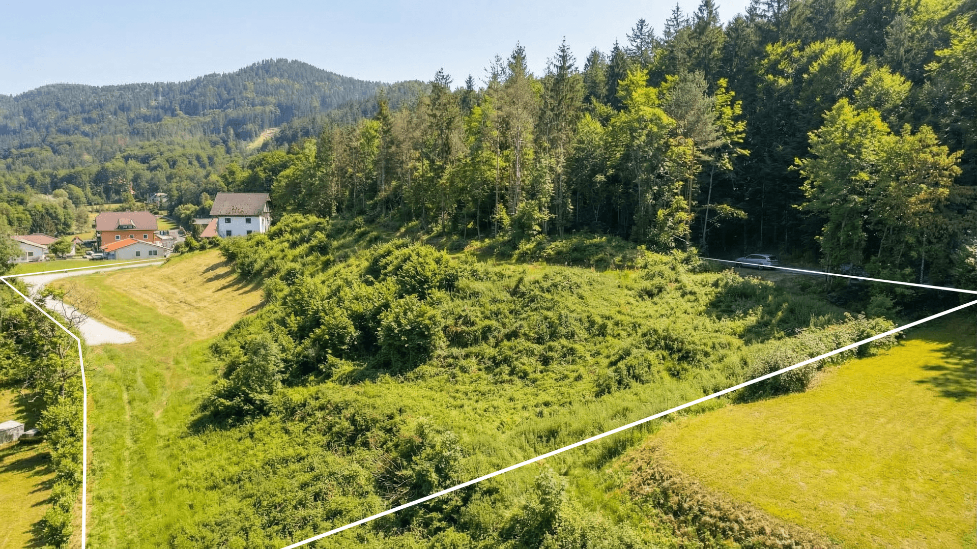Umrandetes, hügeliges Grundstück mit dichter Vegetation und angrenzendem Waldgebiet, bereit zur Bebauung.