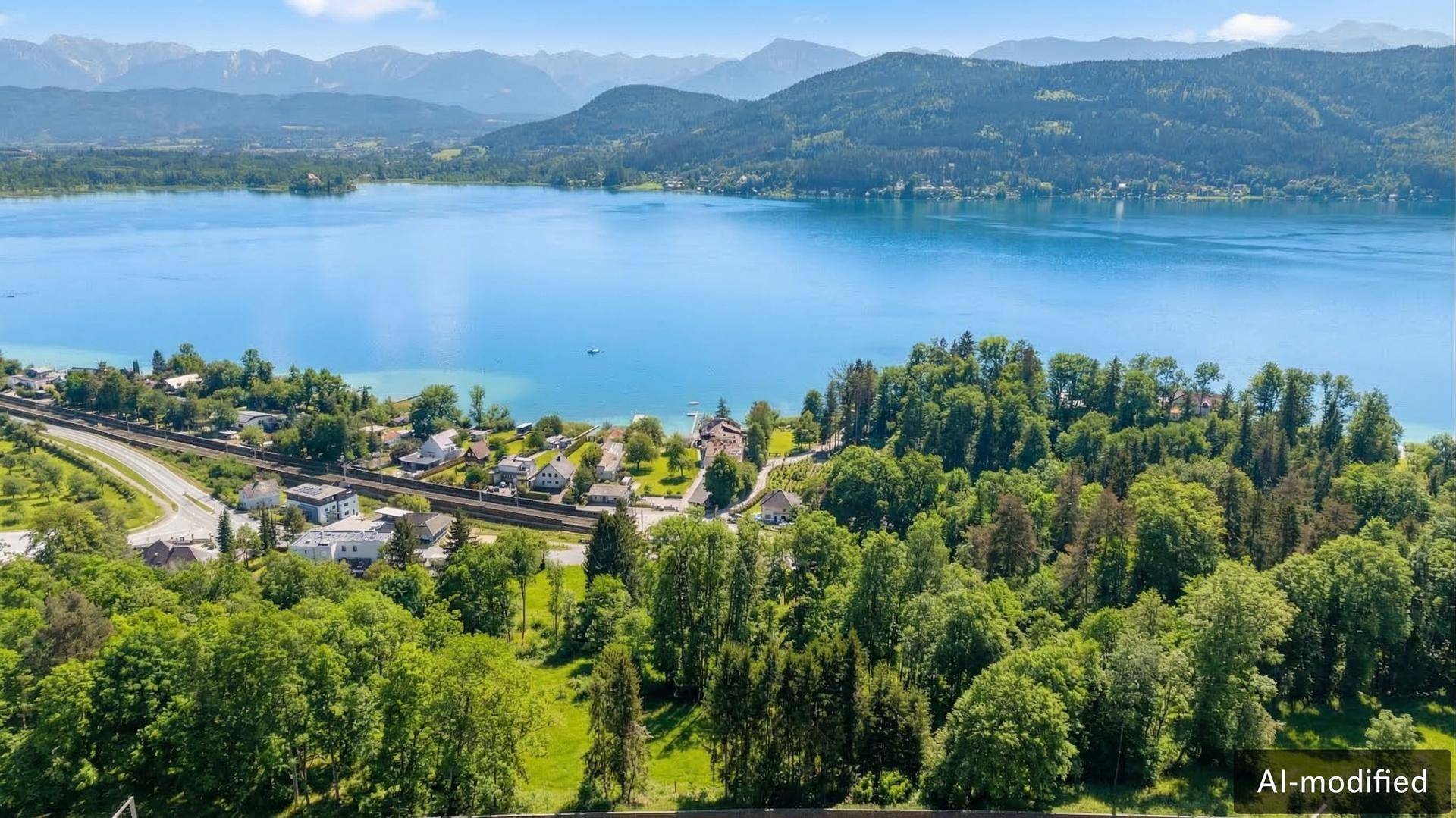 Panoramablick auf einen großen See, umgeben von grünen Wäldern und majestätischen Bergen am Horizont.