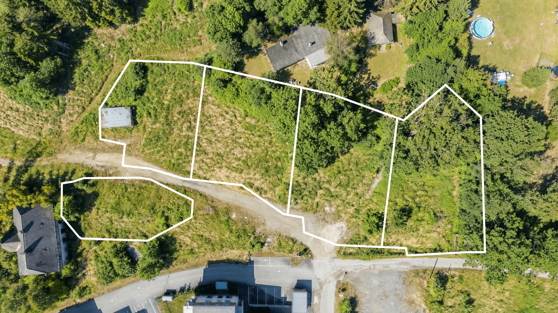 Luftaufnahme eines Grundstücks mit mehreren eingezeichneten Parzellen in einer grünen Umgebung.