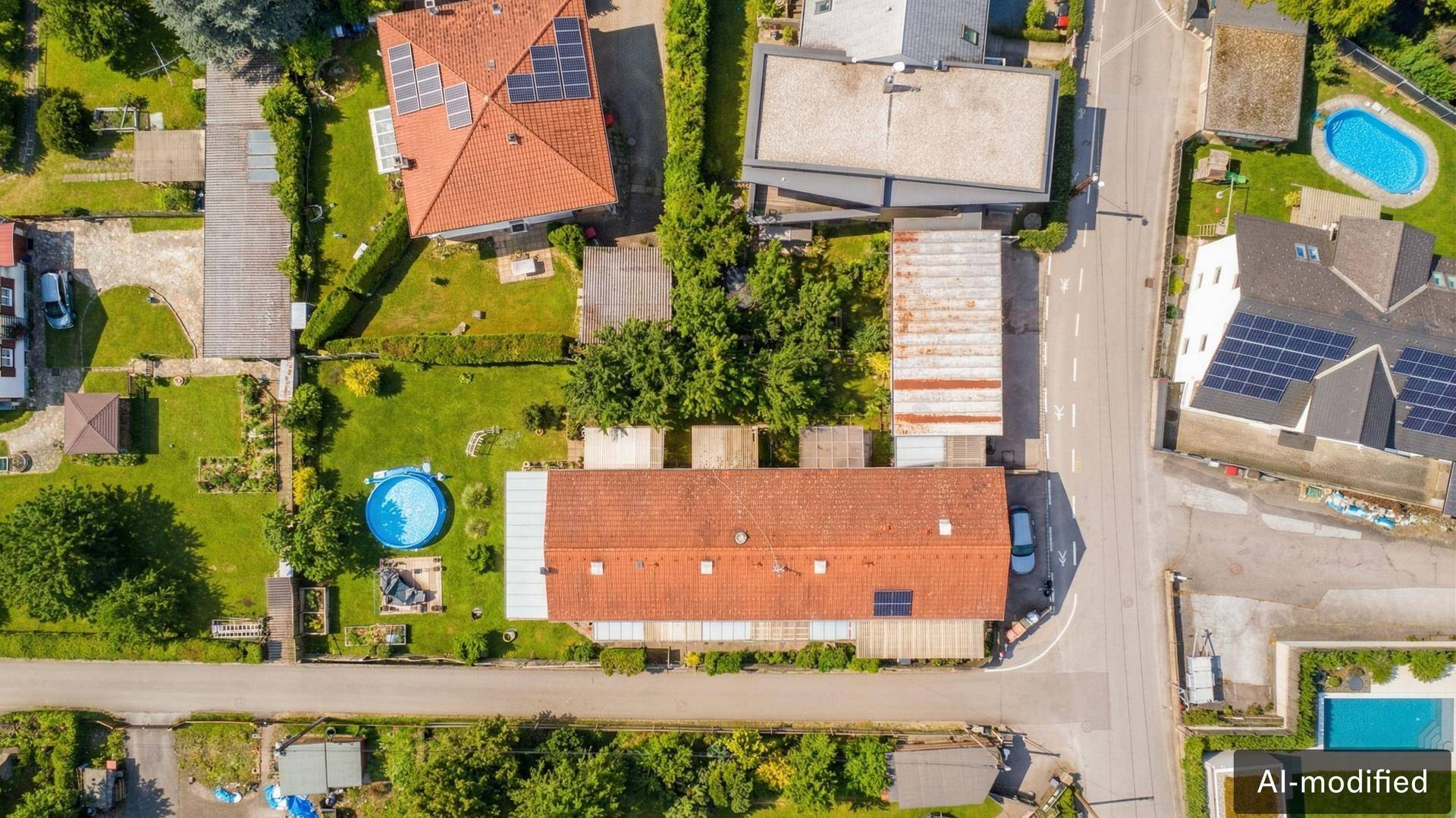 Draufsicht auf eine Wohnsiedlung mit Häusern, Gärten, Straßen und einem Pool.