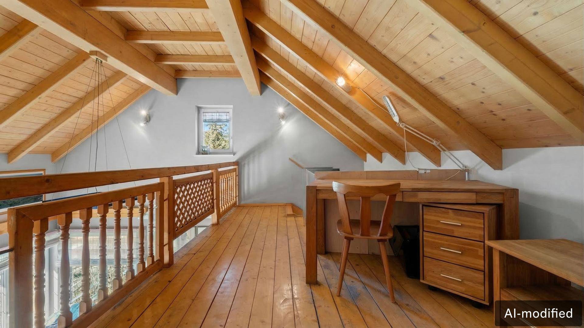 Helle Galerie mit Holzboden, sichtbaren Dachbalken und einem Arbeitsbereich unter der Schräge.