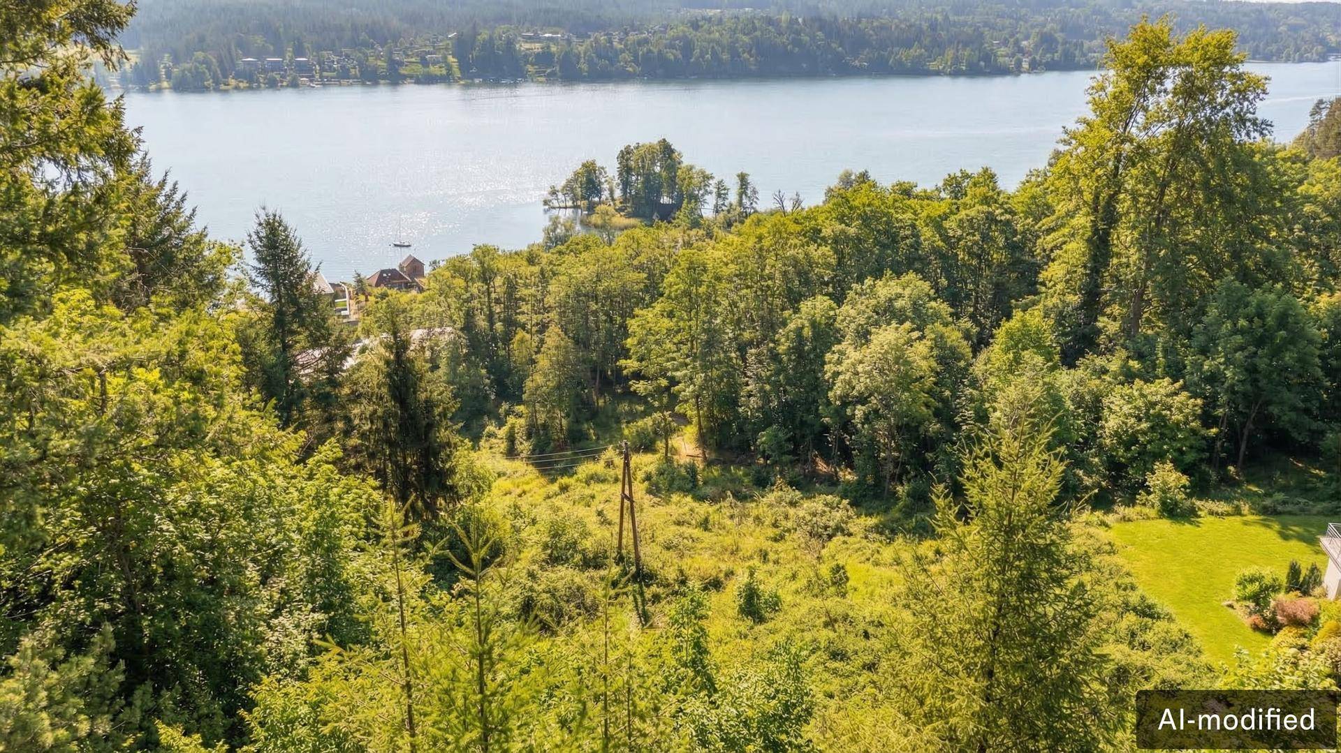 Blick über dichte grüne Wälder auf einen ruhigen See im Hintergrund unter blauem Himmel.