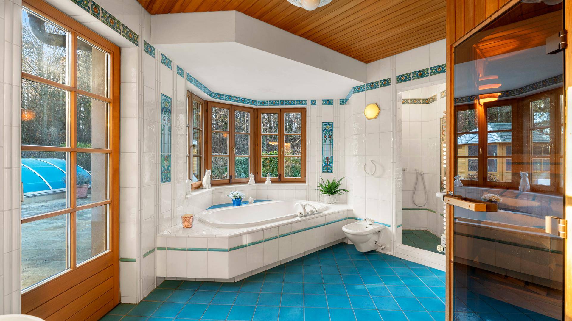 Geräumiges Badezimmer mit blauen Fliesen, Badewanne, Bidet, Dusche und integrierter Sauna.