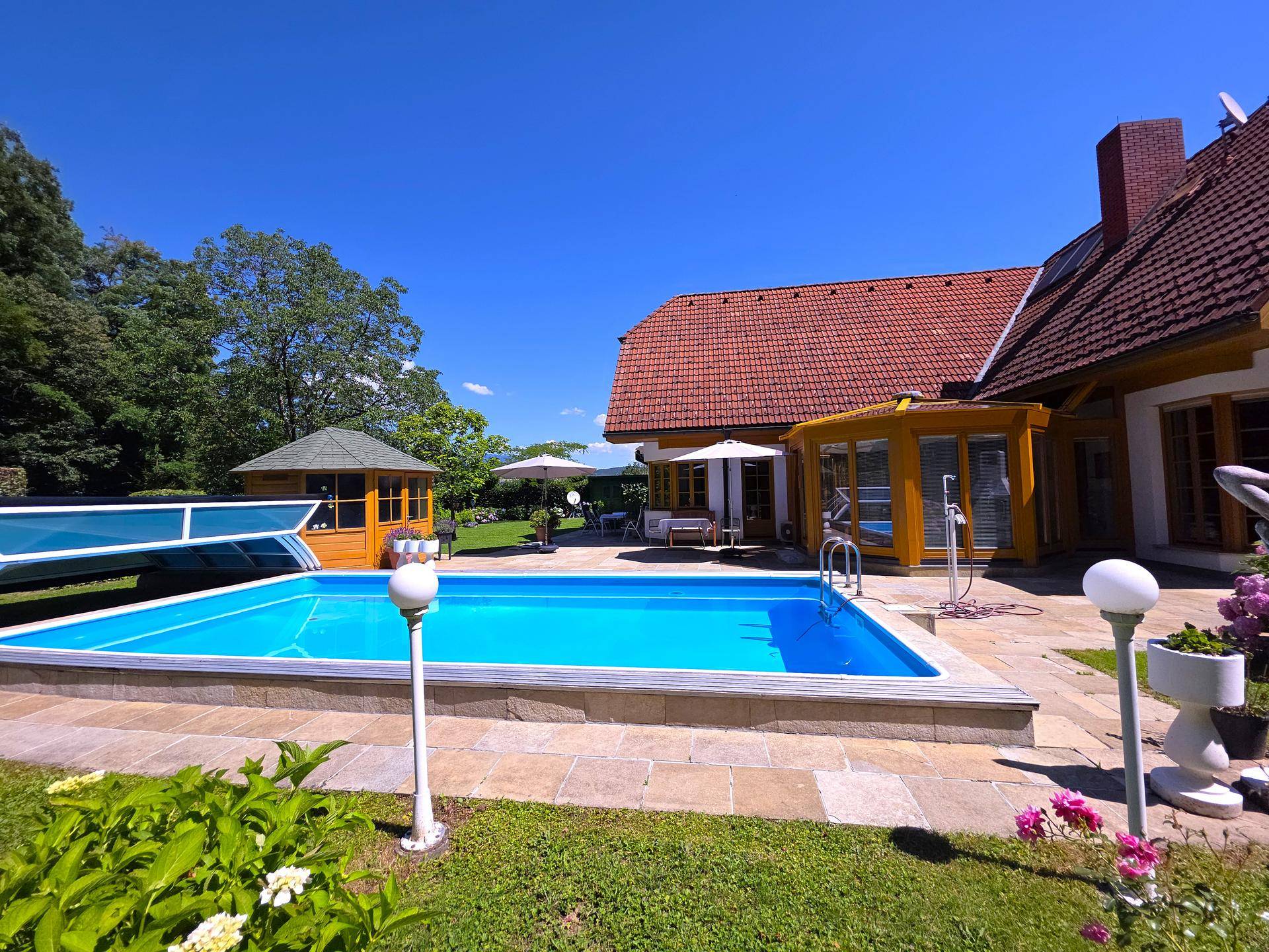 Gepflegter Gartenbereich mit großem Pool, Sonnenterrasse und Blick auf das Haus.