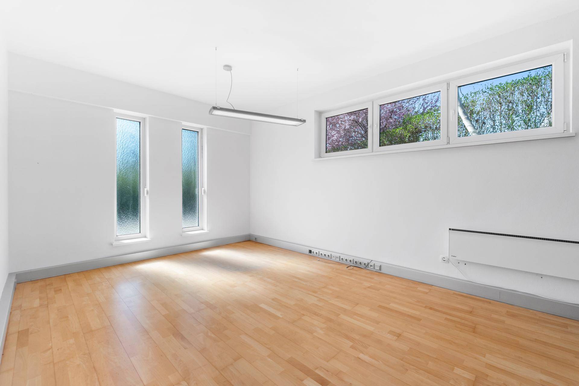 Leerer Raum mit Holzparkettboden und mehreren Fenstern, ideal als Büro oder Schlafzimmer.