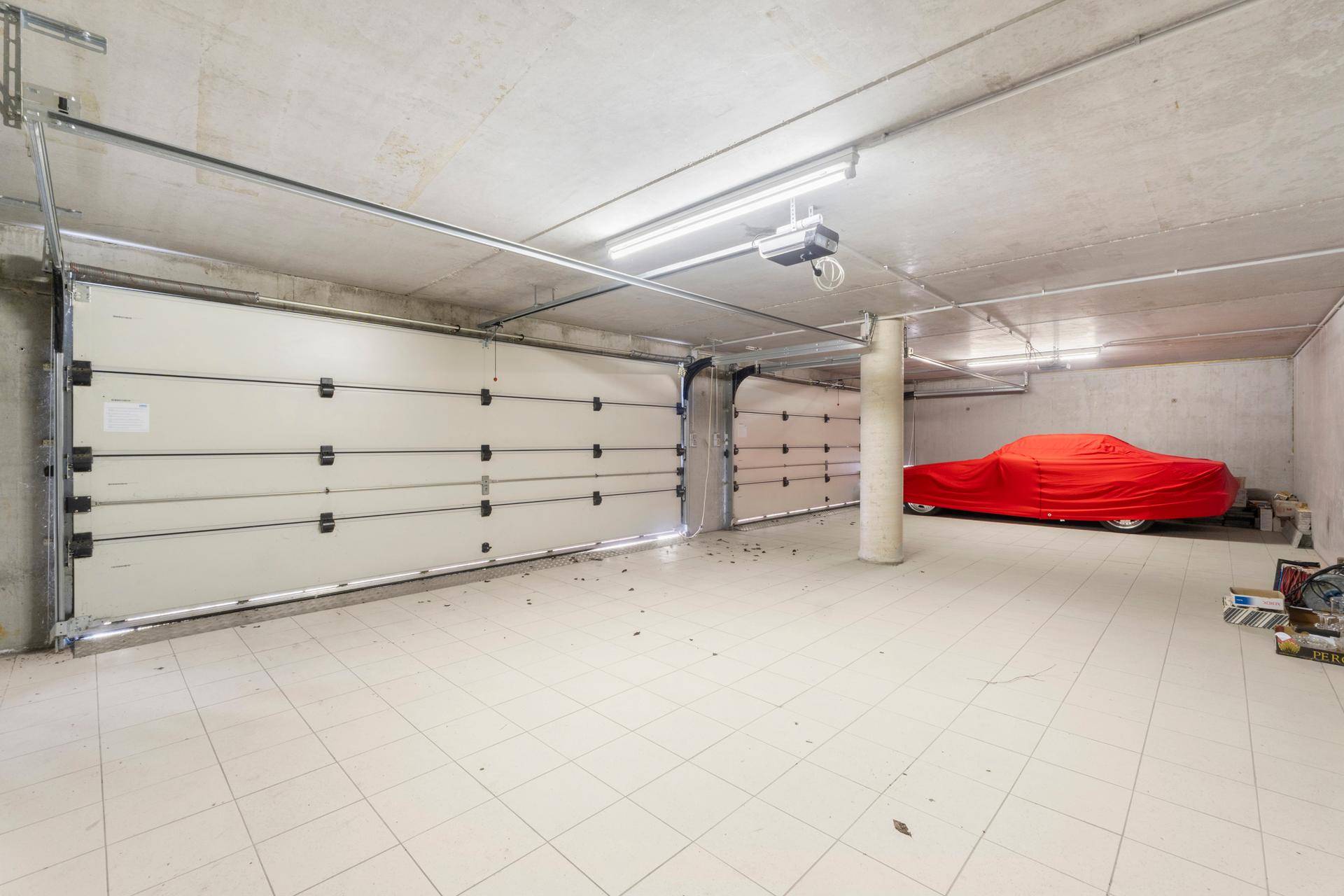 Geräumige Garage mit zwei Toren und Fliesenboden, bietet Platz für mehrere Fahrzeuge.