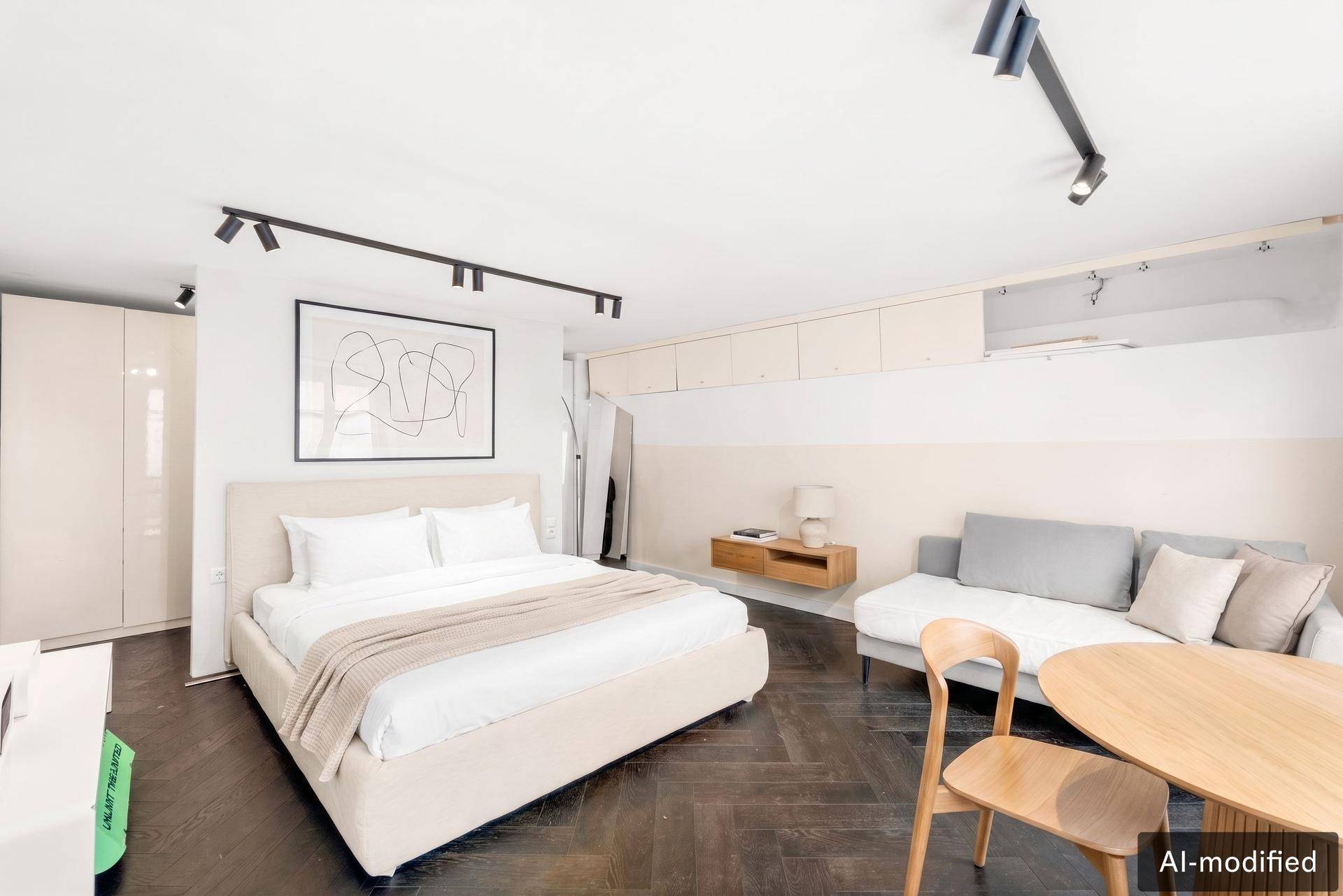 Modernes Schlafzimmer mit integriertem Wohnbereich, dunklem Parkett und Einbauschränken.