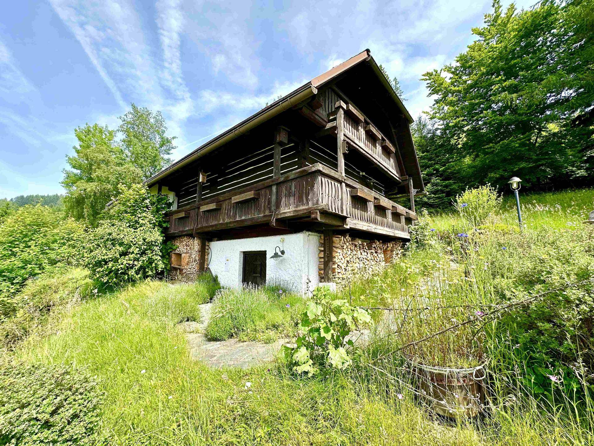 Rustikales Holzchalet auf einem Hügel mit gestapeltem Brennholz und umgeben von üppiger Natur.