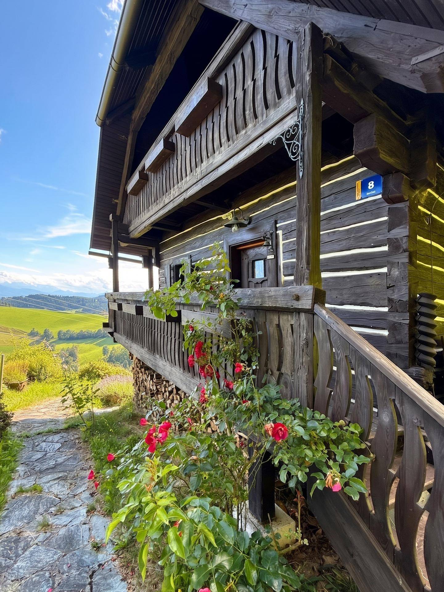Traditioneller Holzbalkon mit geschnitzten Details und weitem Blick über die sonnige Landschaft.