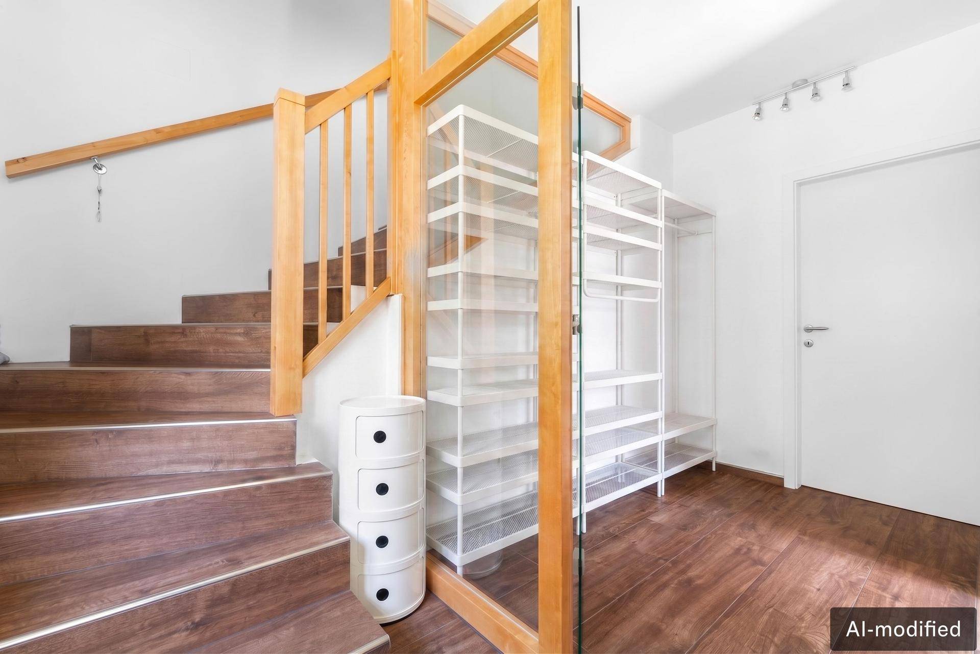 Heller Flurbereich mit Holztreppe, Glasgeländer und praktischen weißen Regalsystemen.