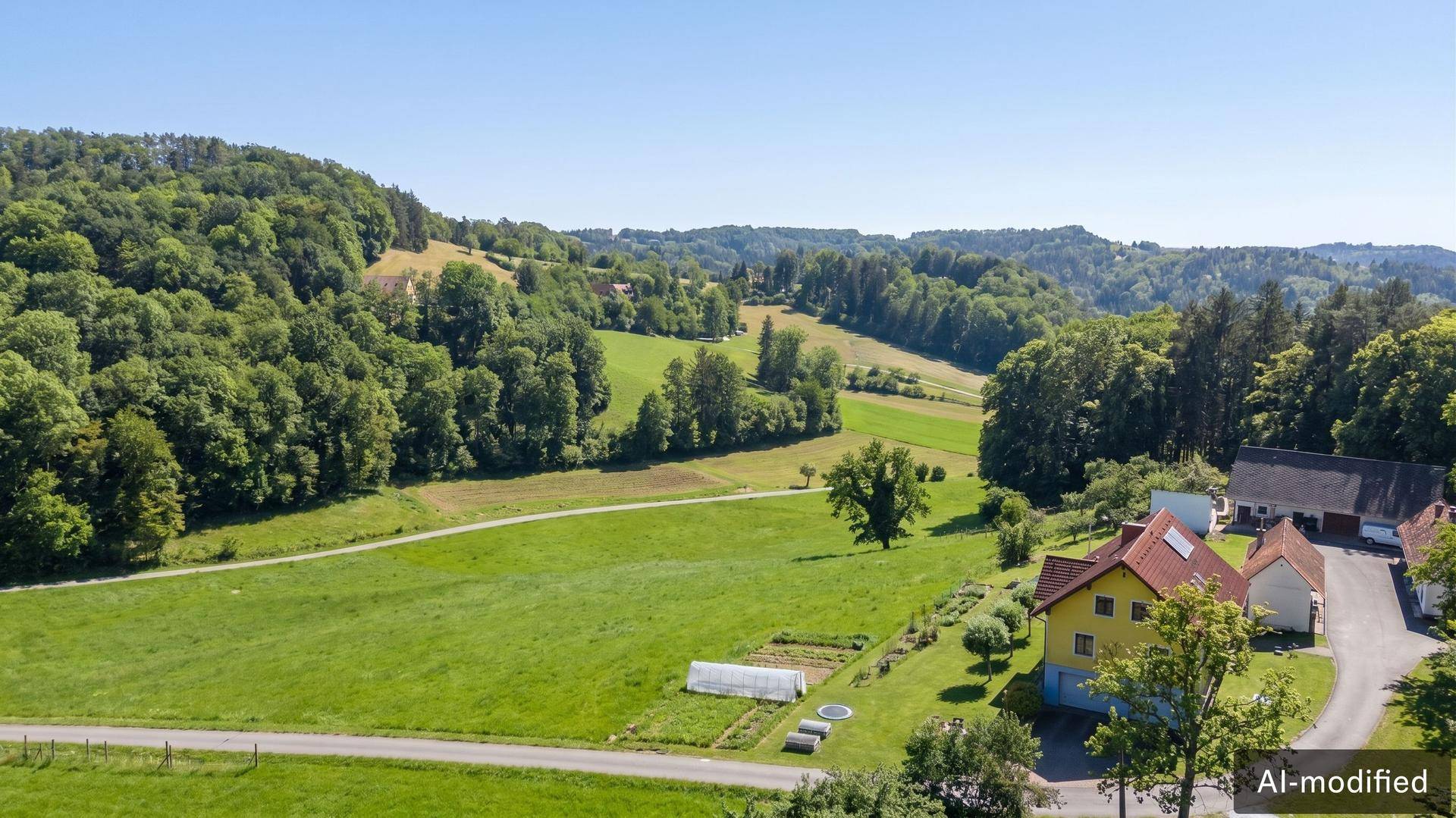 Weitläufige Luftaufnahme des Anwesens, eingebettet in eine hügelige, grüne Landschaft mit Wäldern.