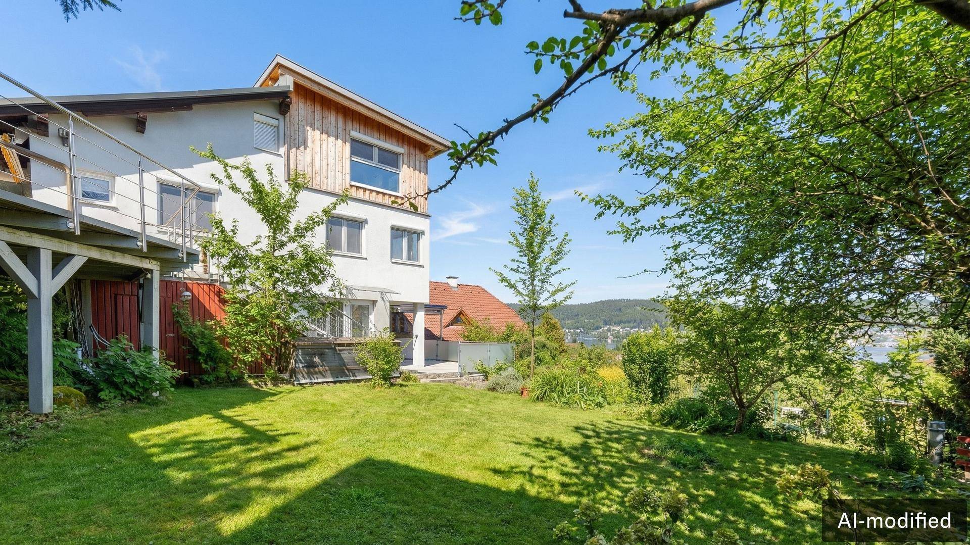 Gartenbereich mit Rasenfläche und Bäumen neben dem Haus, mit Fernblick auf die Landschaft.