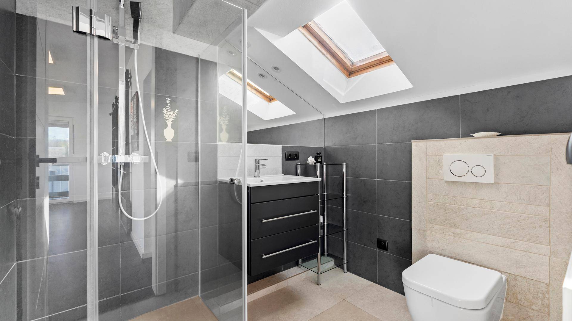 Modernes Badezimmer mit begehbarer Dusche, Dachfenstern und grauen Fliesen.