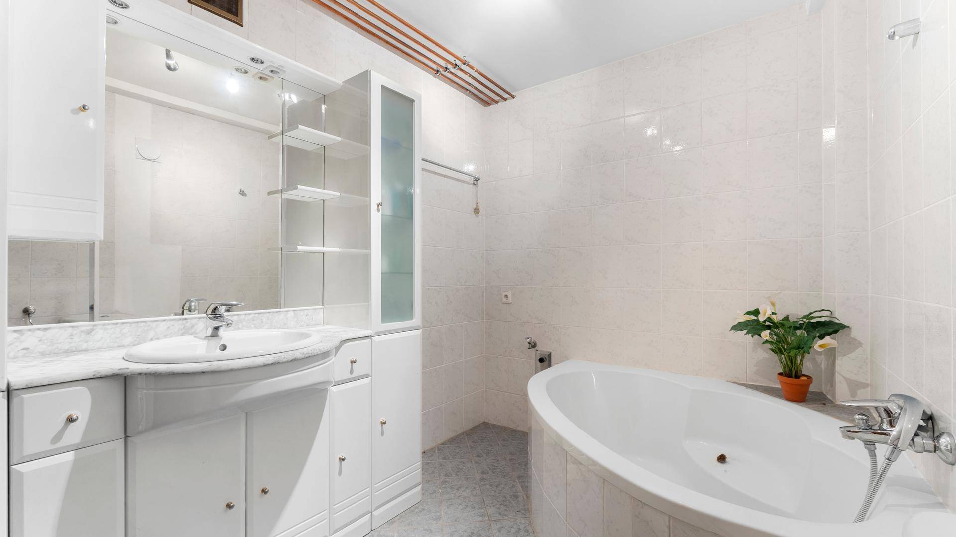 Helles Badezimmer mit Badewanne, Waschtisch und weißen Fliesen.