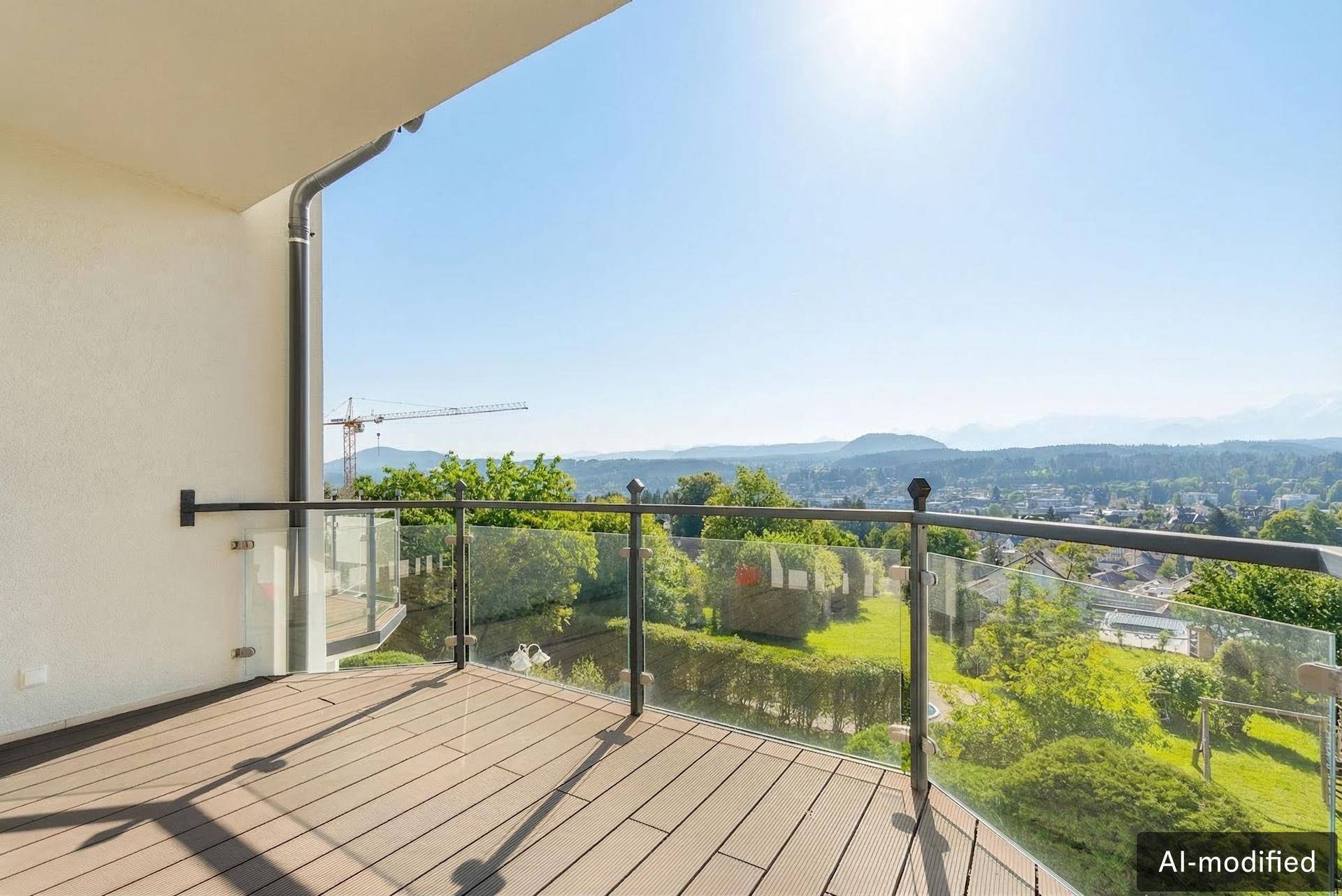 Geräumiger Balkon mit Glasgeländer und weitem Blick über die Stadt und Berge.