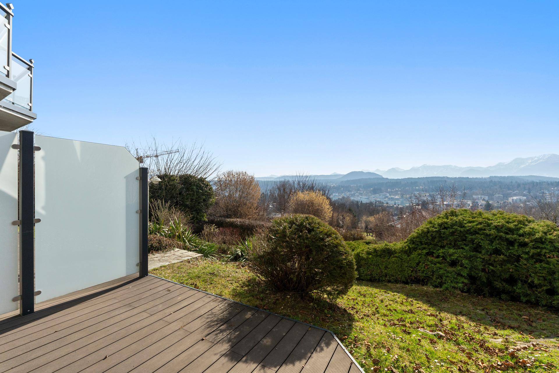 Sonniger Terrassenbereich mit Holzboden und Panoramablick auf die Landschaft und Berge.