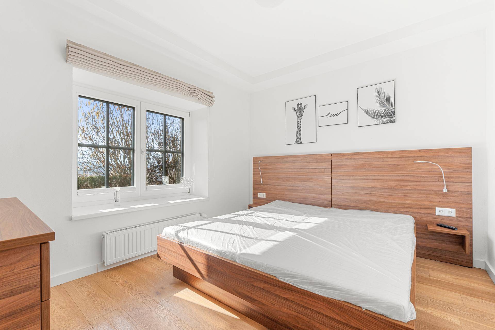 Gemütliches Schlafzimmer mit Holzbett, Parkettboden und Fenster mit Ausblick.
