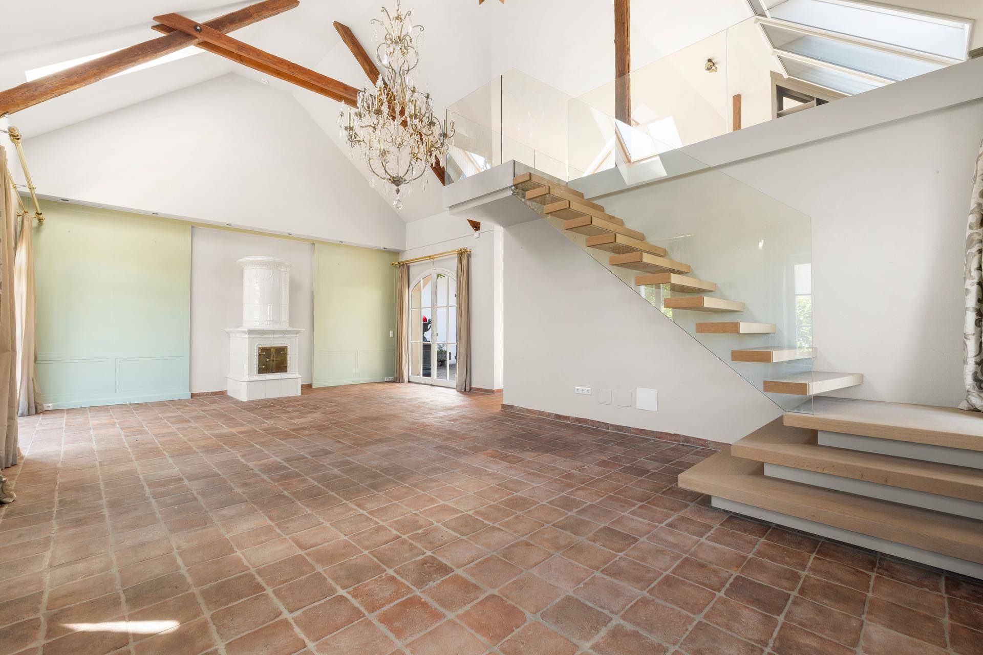 Großzügiges Wohnzimmer mit hohen Decken, Holzbalken und einem eleganten Kachelofen.