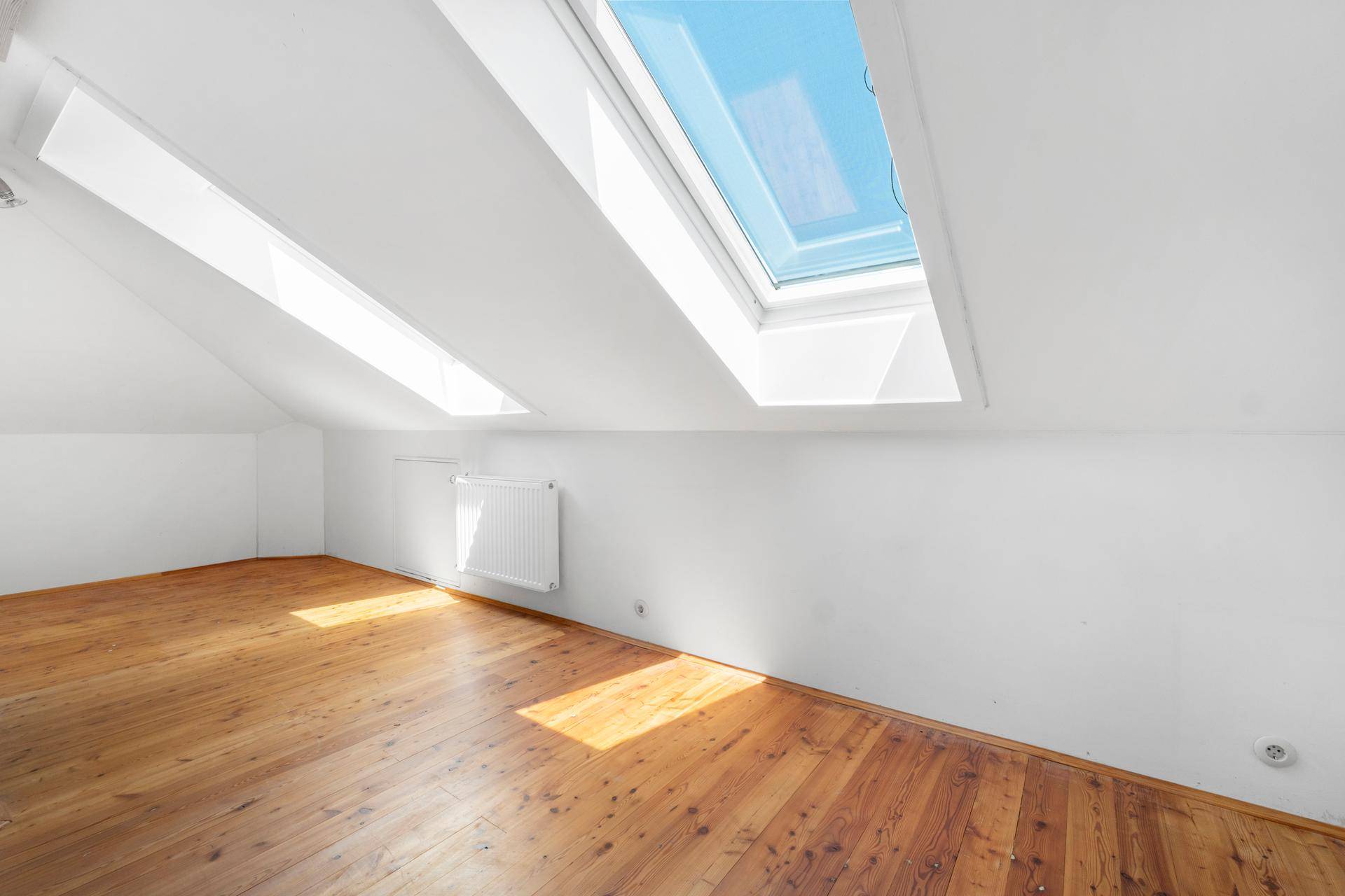 Lichtdurchfluteter Dachbodenraum mit zwei großen Dachfenstern und rustikalem Holzfußboden.