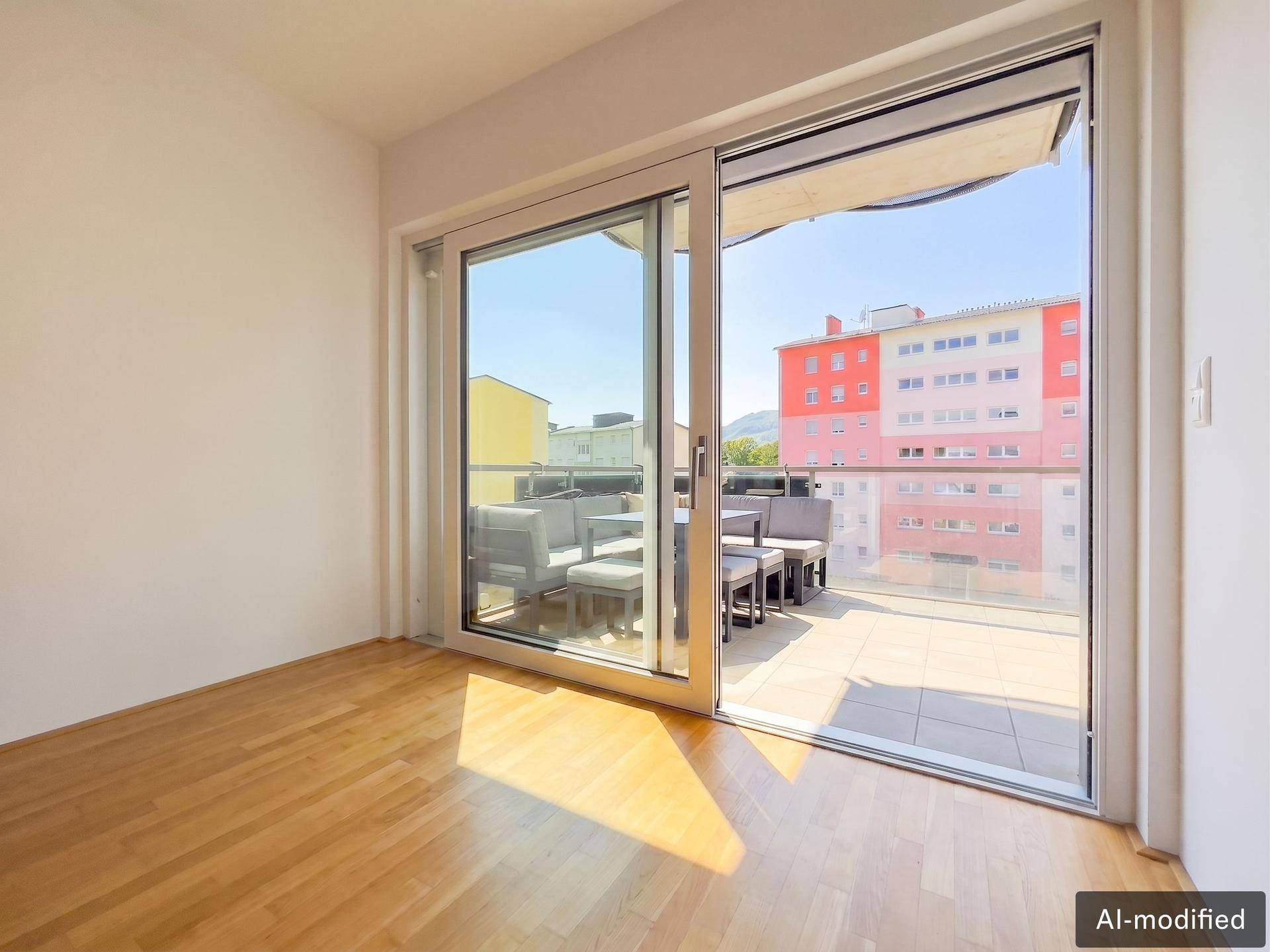 Lichtdurchfluteter Raum mit Holzboden und großem Schiebefenster zum möblierten Außenbereich.