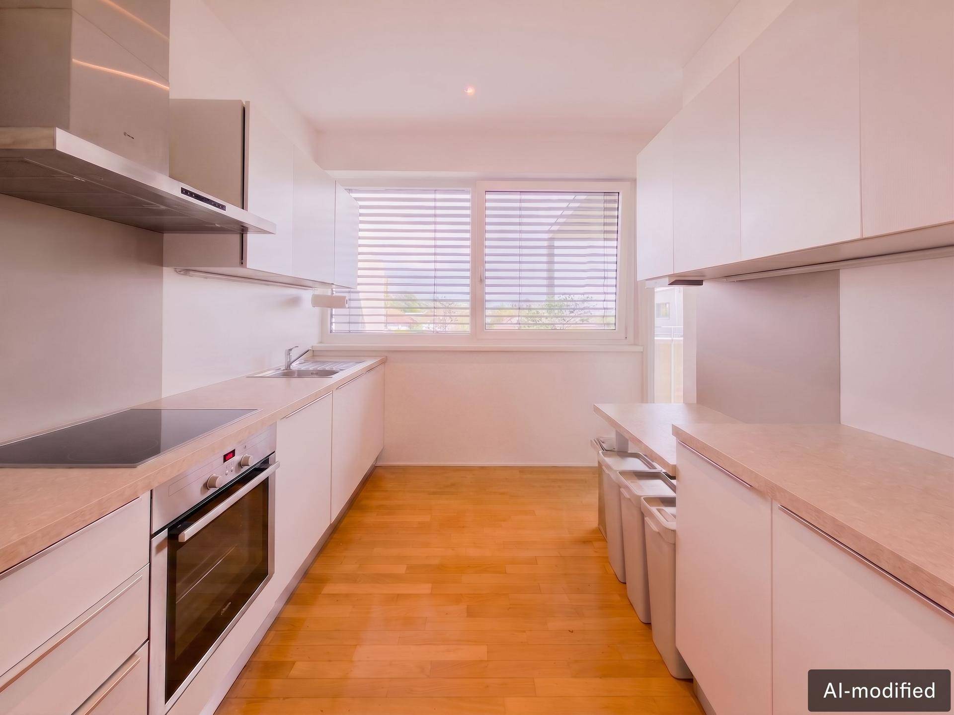 Moderne Küche mit weißen Schränken, Holzboden und Fenster für natürliches Licht.