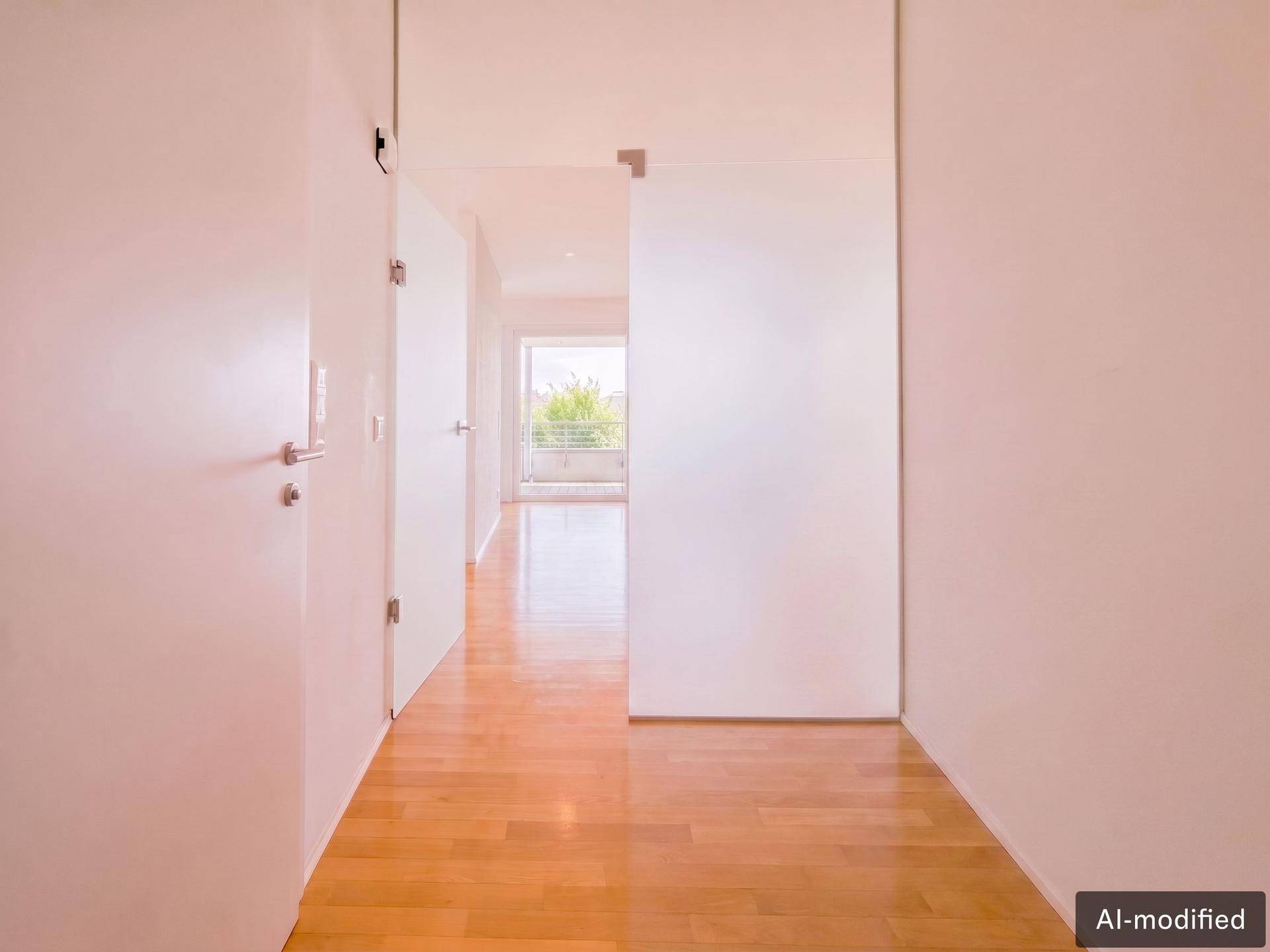 Heller Flur mit Holzboden und modernen Glastüren, die zu weiteren Räumen führen.