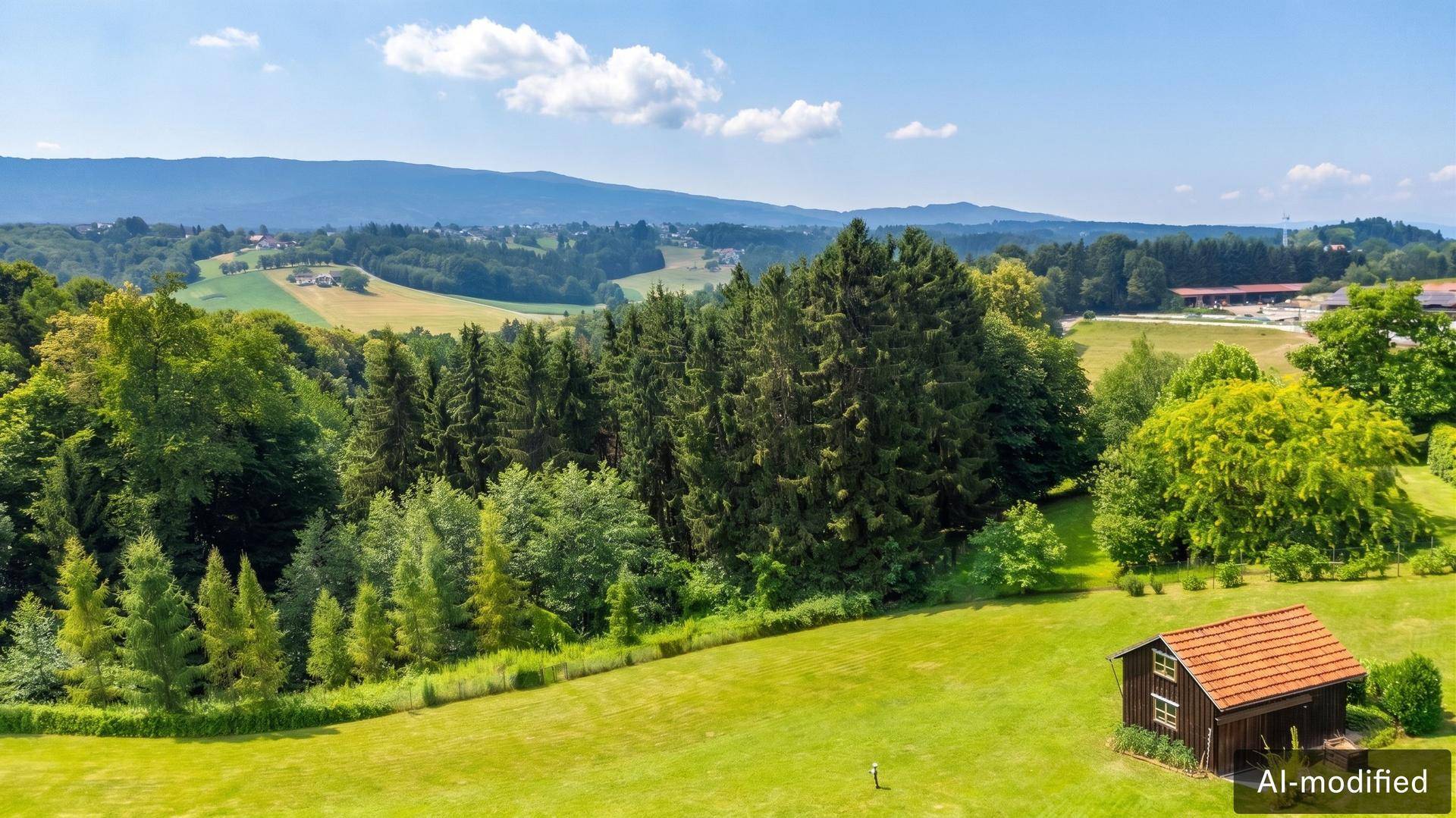 Malerische Landschaft mit grünen Wäldern, Feldern und Bergen im Hintergrund unter blauem Himmel.