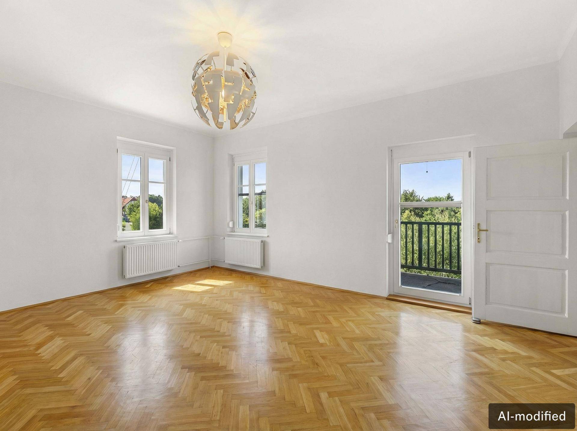 Geräumiges Zimmer mit Fischgrätparkett und Zugang zu einem Balkon, bietet viel natürliches Licht.