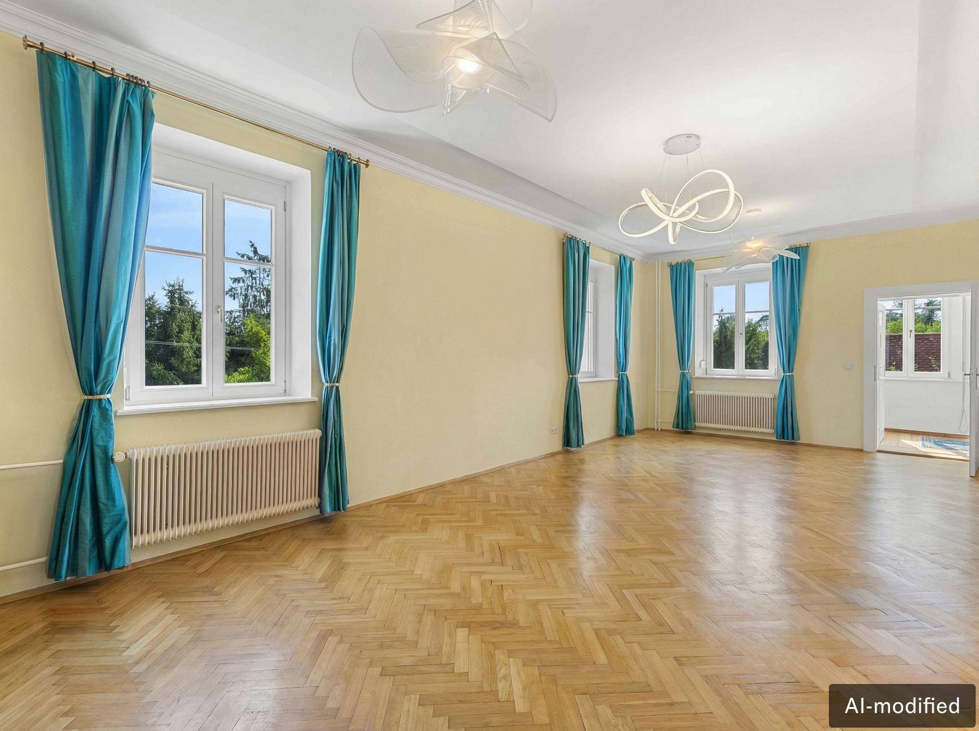 Geräumiges Wohnzimmer mit Fischgrätparkett, hohen Decken und großen Fenstern mit Blick ins Grüne.