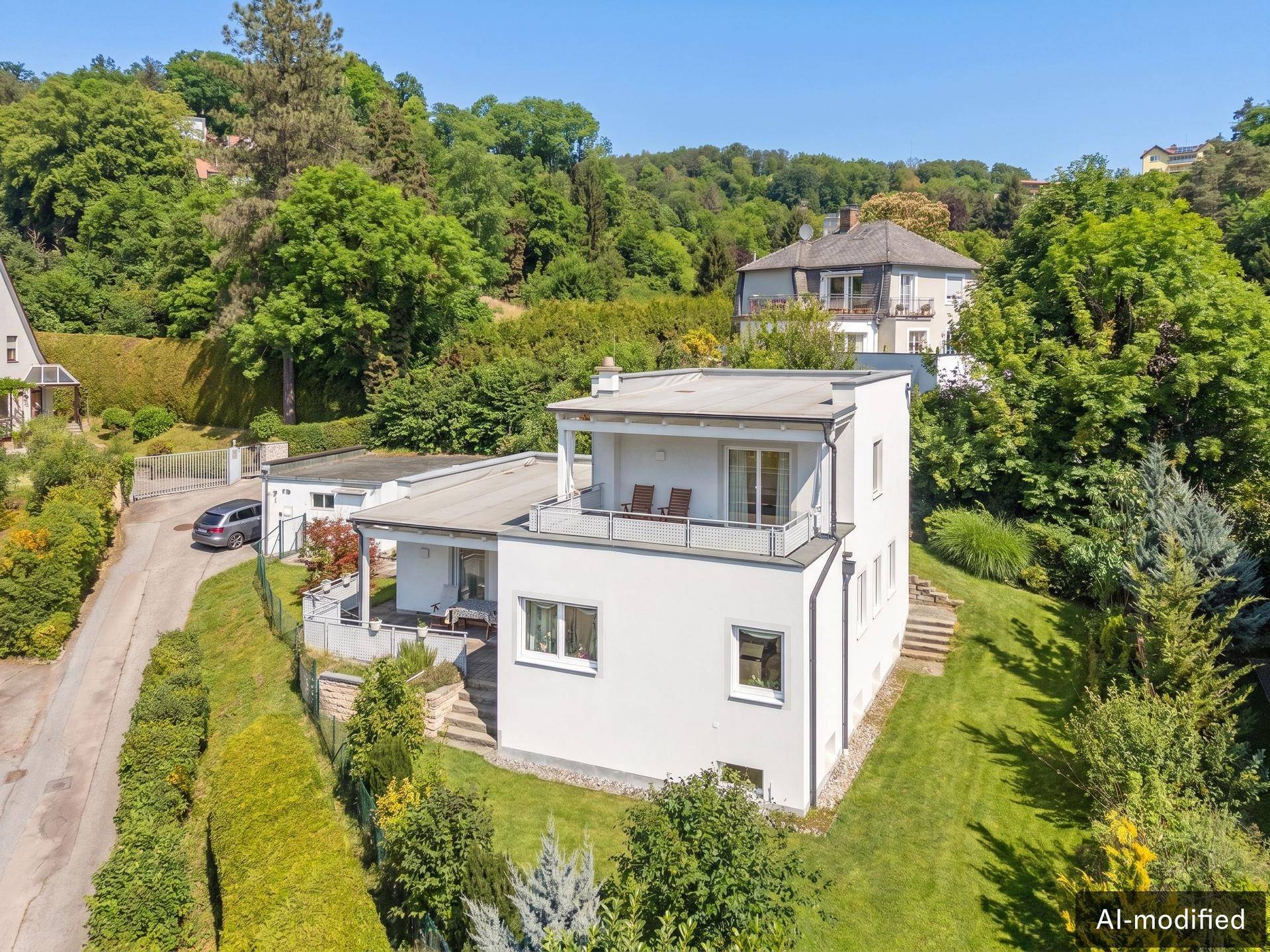 Moderne Architektur mit mehreren Terrassen und gepflegtem Garten in grüner Hanglage.