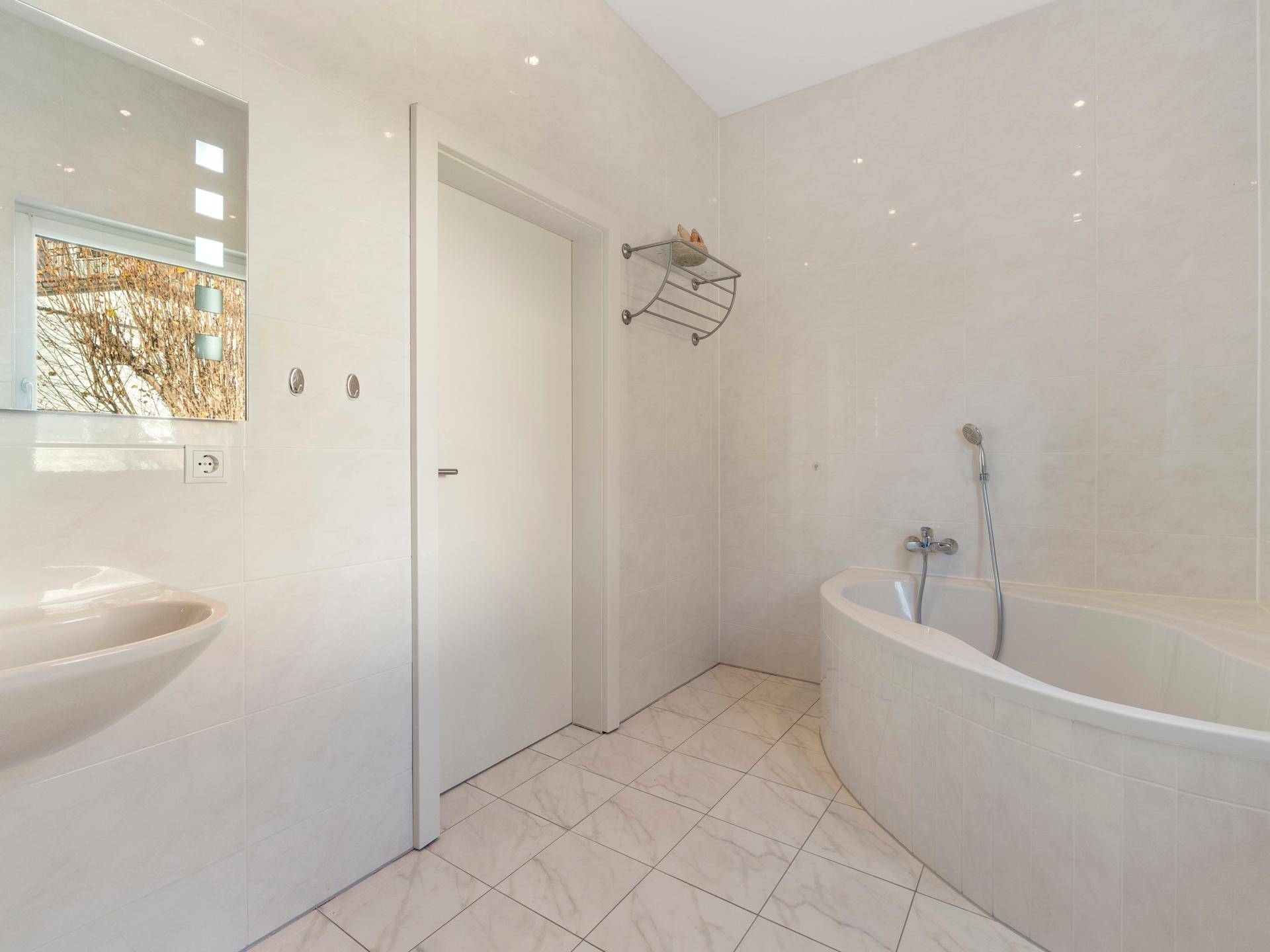 Helles Badezimmer mit Eckbadewanne, Waschbecken und großem Spiegel, modern und funktional.