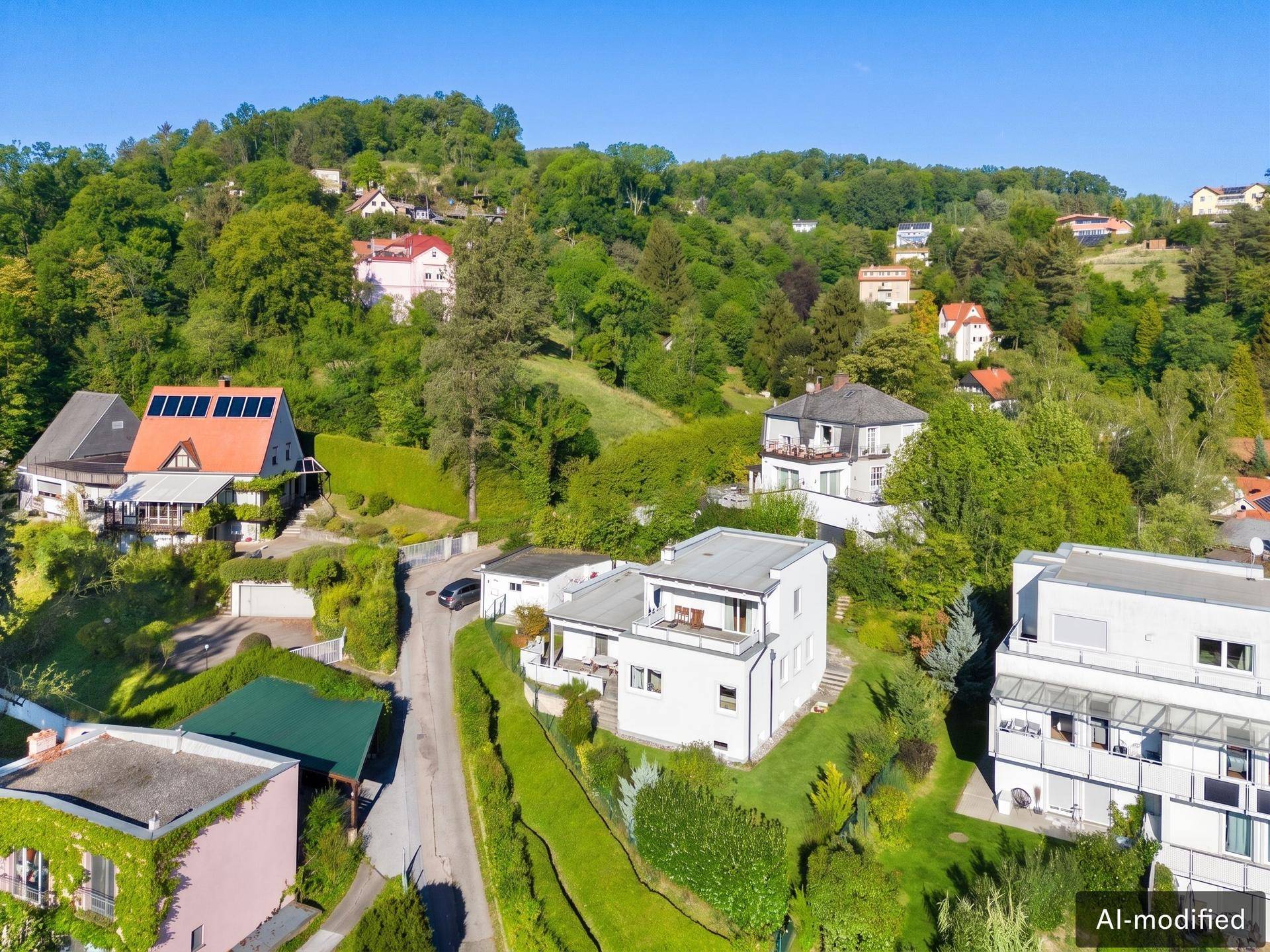 Luftaufnahme der modernen Villa in einer grünen Wohngegend mit Hügellandschaft und anderen Häusern.
