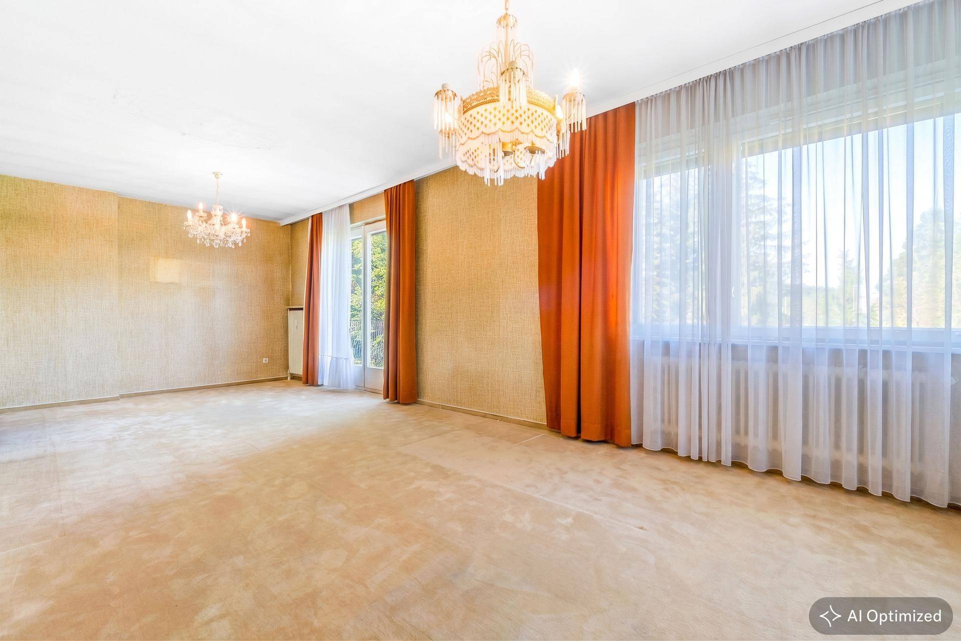 Geräumiger Wohnbereich mit Teppichboden, gemusterter Tapete und großen Fenstern mit Vorhängen.