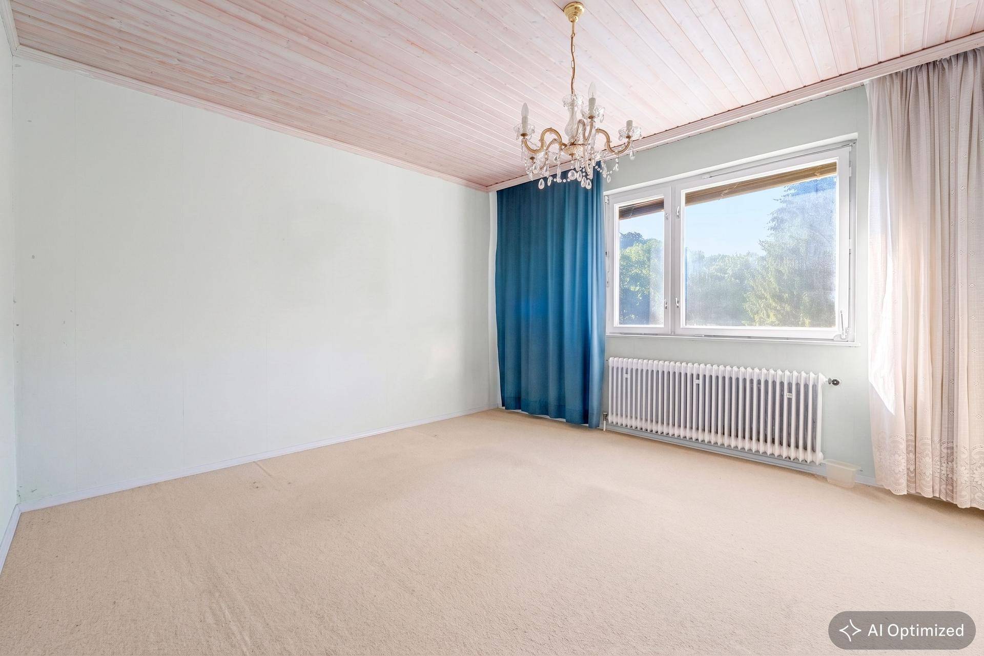 Schlafzimmer mit Teppichboden, hellblauen Wänden und einer Holzdecke, hell durch große Fenster.