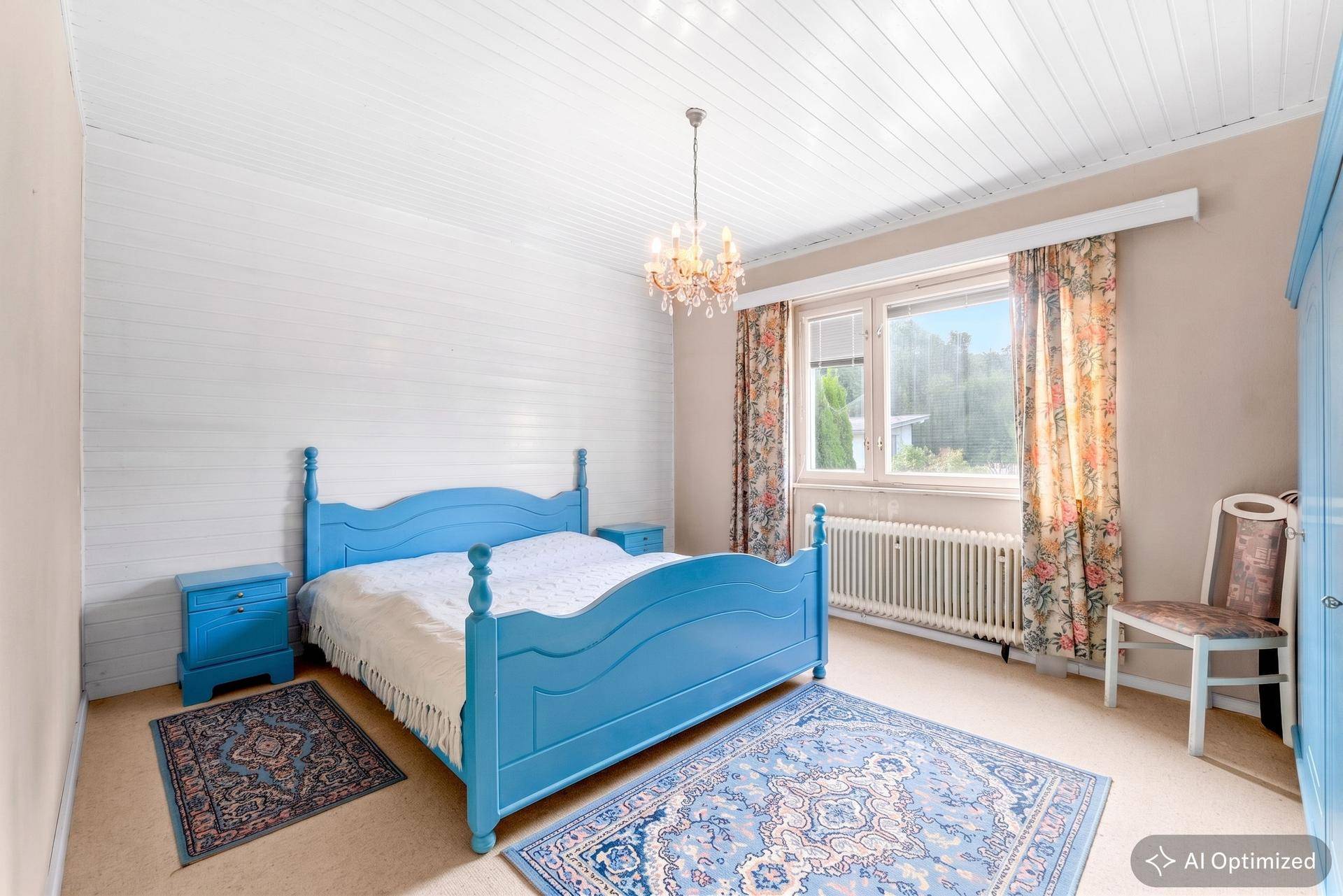 Schlafzimmer mit blauem Holzdoppelbett, passenden Nachttischen und Teppichboden.