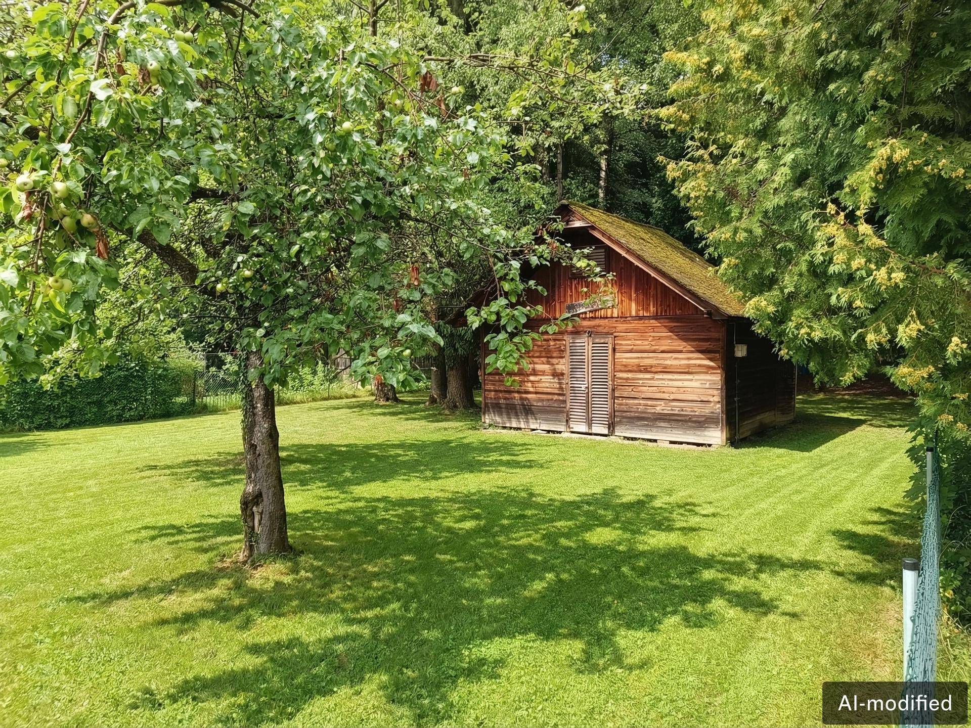 Rustikales Holzgartenhaus unter einem Baum auf einer gepflegten Rasenfläche.