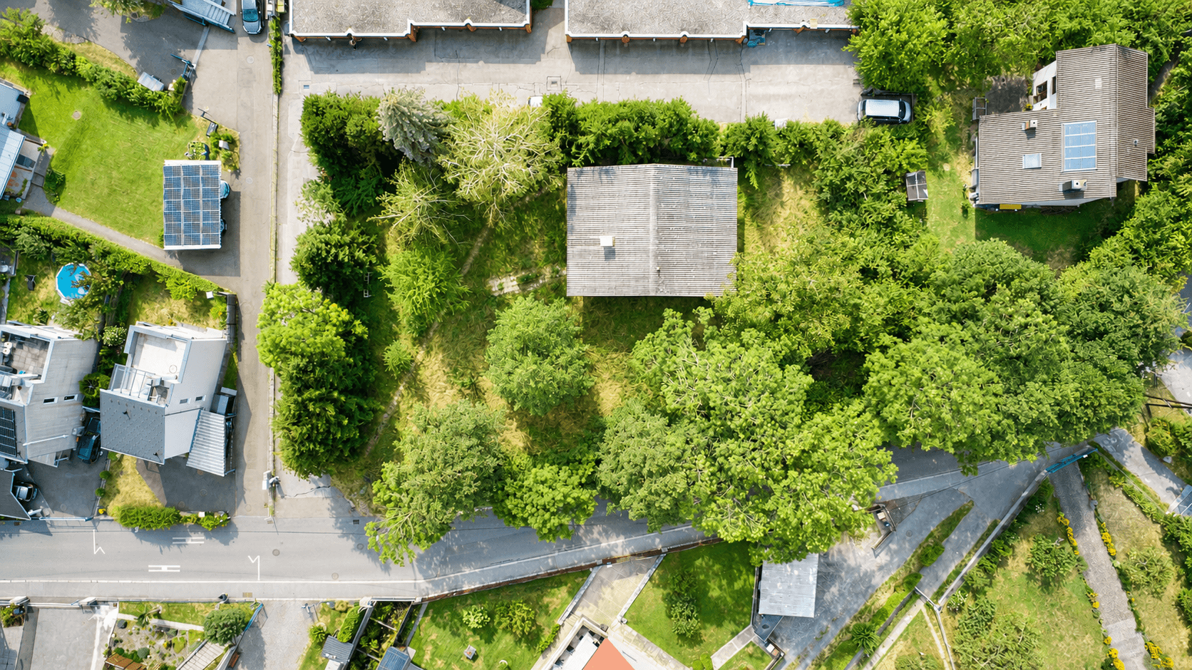 Draufsicht auf ein Wohnhaus mit großem Garten, umgeben von Straßen und weiteren Gebäuden.