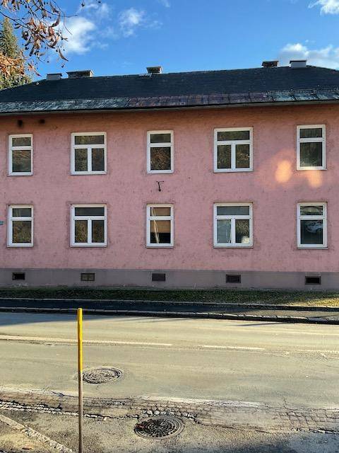 Vorderansicht eines älteren Gebäudes mit rosafarbener Fassade und zahlreichen Fenstern zur Straße.