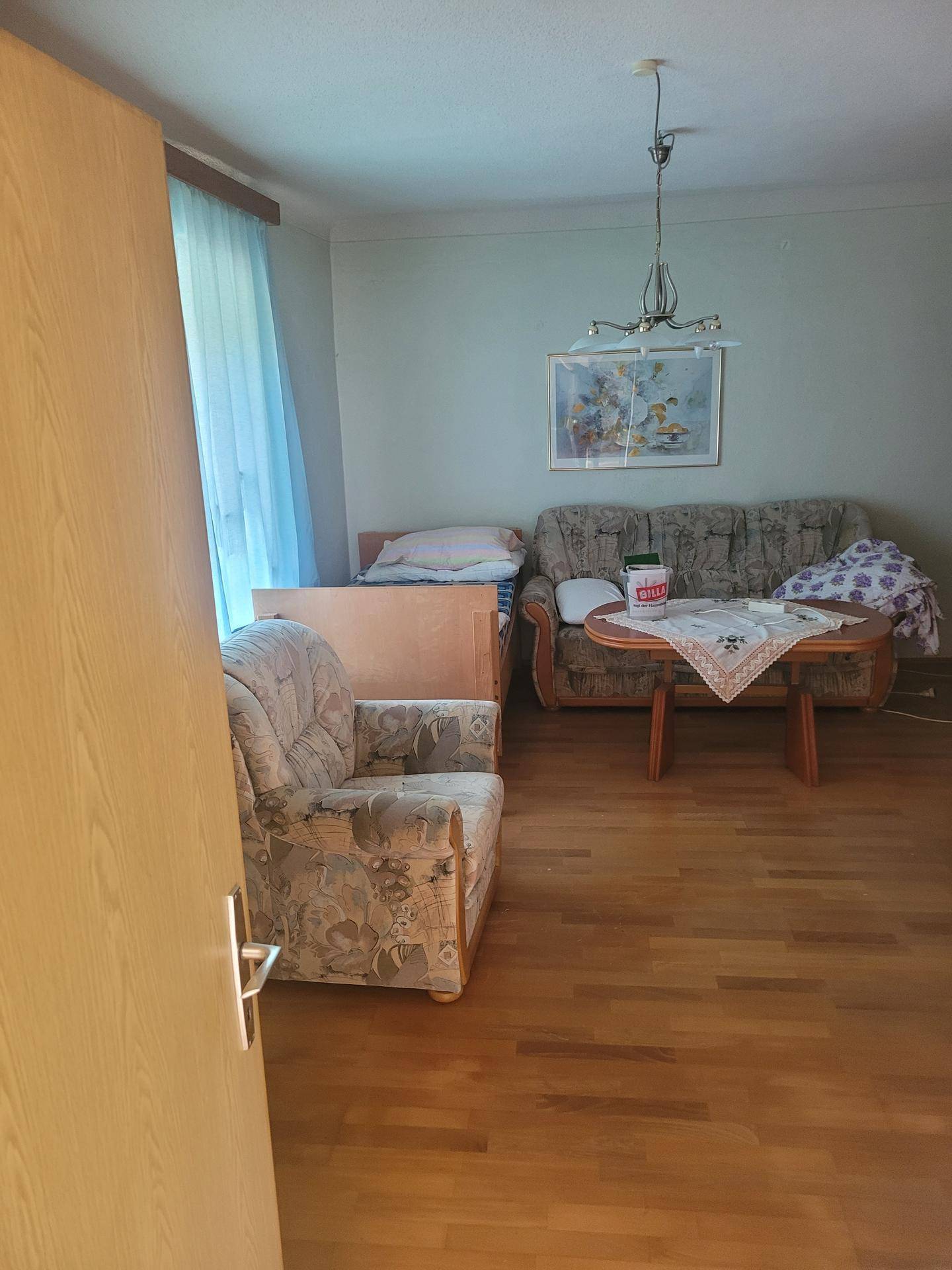 Wohnzimmer mit hellem Laminatboden, traditionellen Möbeln und einem Sofa.