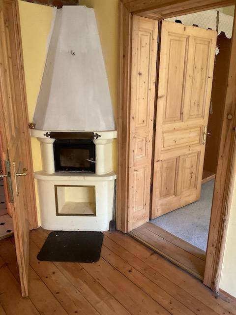 Zimmer mit Holzdielenboden und einem traditionellen Kamin als zentrales Element.