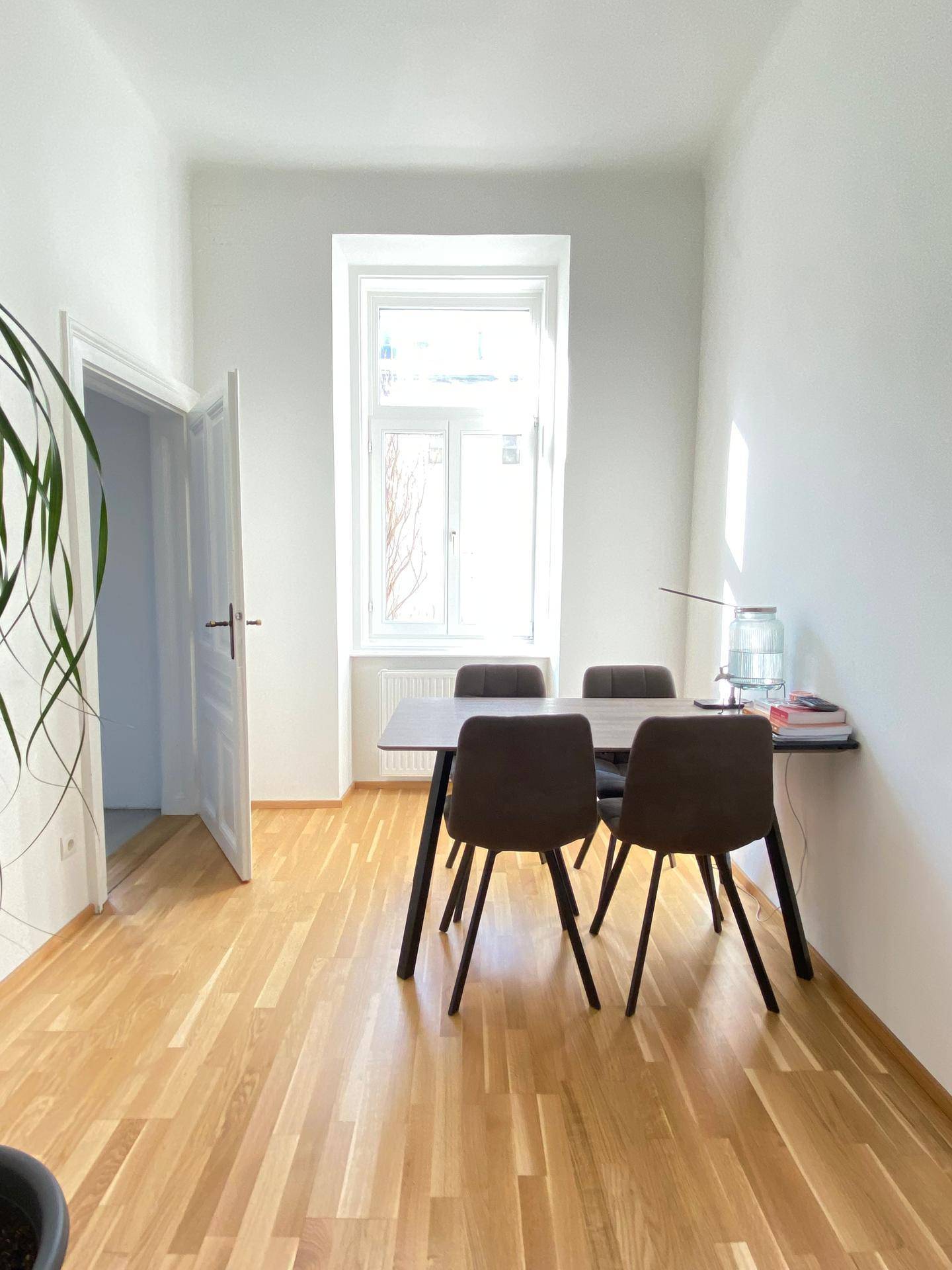 Heller Essbereich mit Holzboden, modernem Esstisch und Stühlen am Fenster.