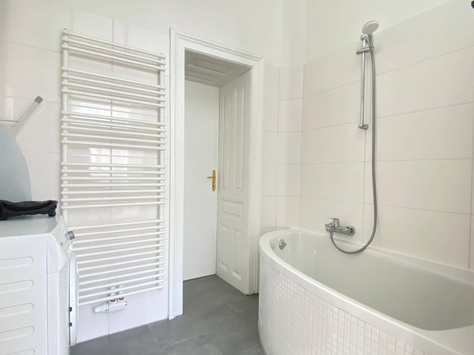 Badezimmer mit Badewanne, beheiztem Handtuchhalter und Waschmaschine.