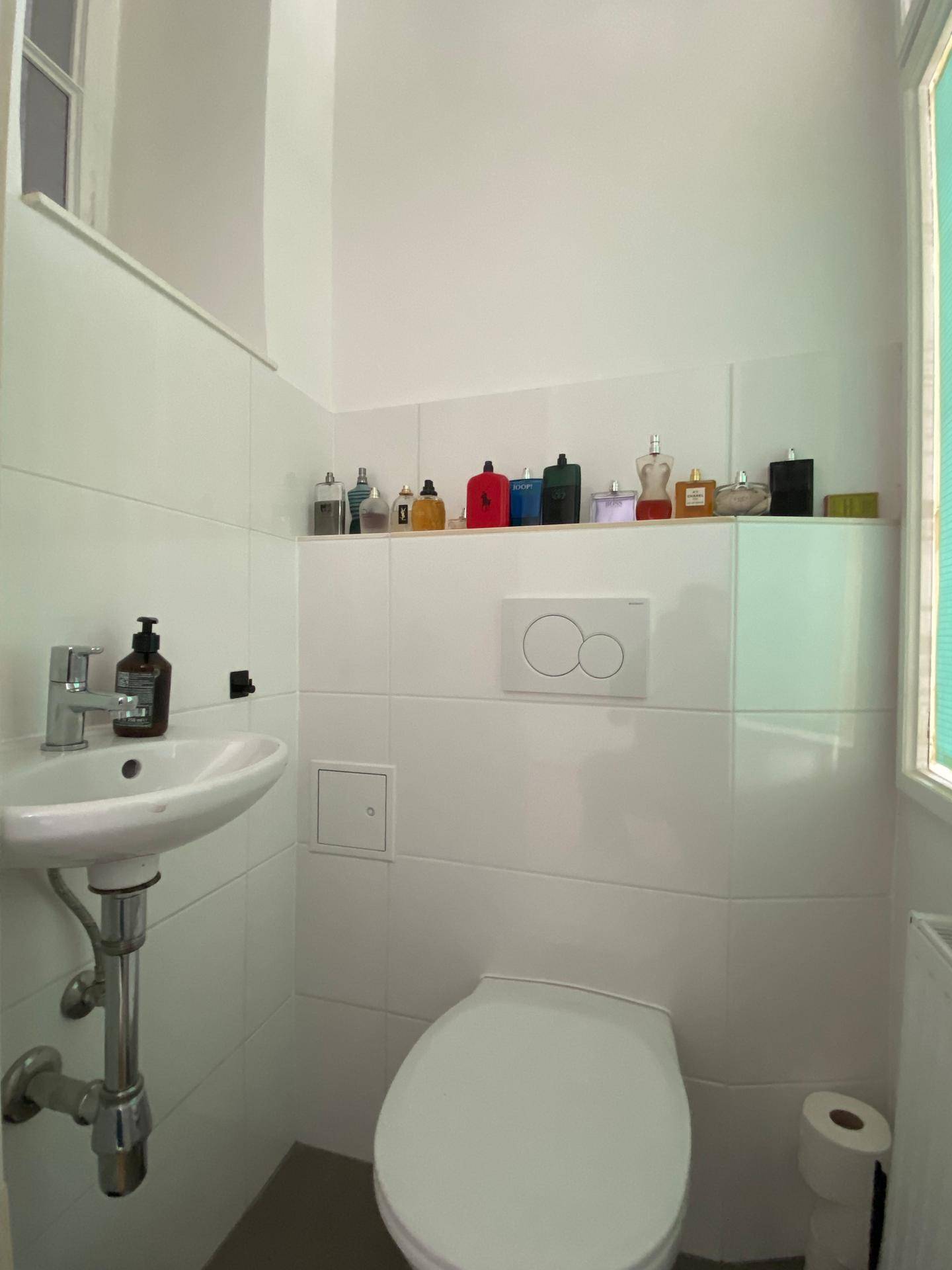 Kleines Gäste-WC mit Waschbecken, wandhängendem WC und Fenster.