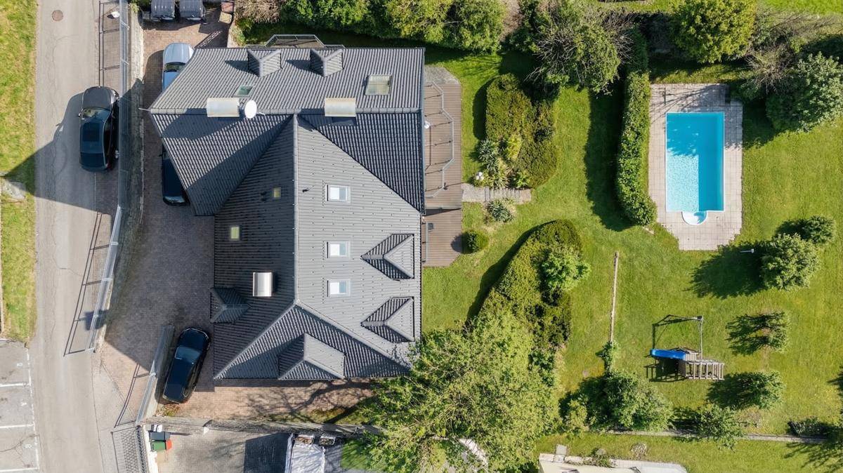 Draufsicht auf das Anwesen mit gepflegtem Garten, Swimmingpool und Spielbereich.