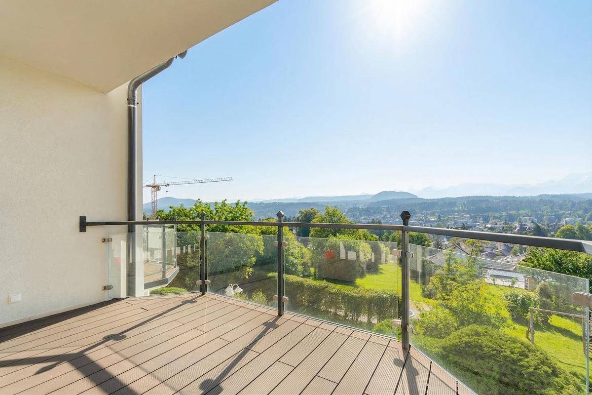 Geräumiger Balkon mit Holzboden und Glasgeländer, bietet eine weite Aussicht.
