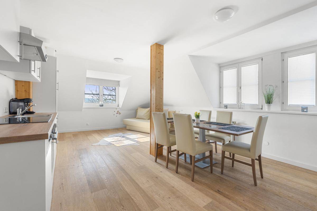 Offene Wohnküche mit Holzboden, Dachschrägen und Essbereich unter dem Dach.