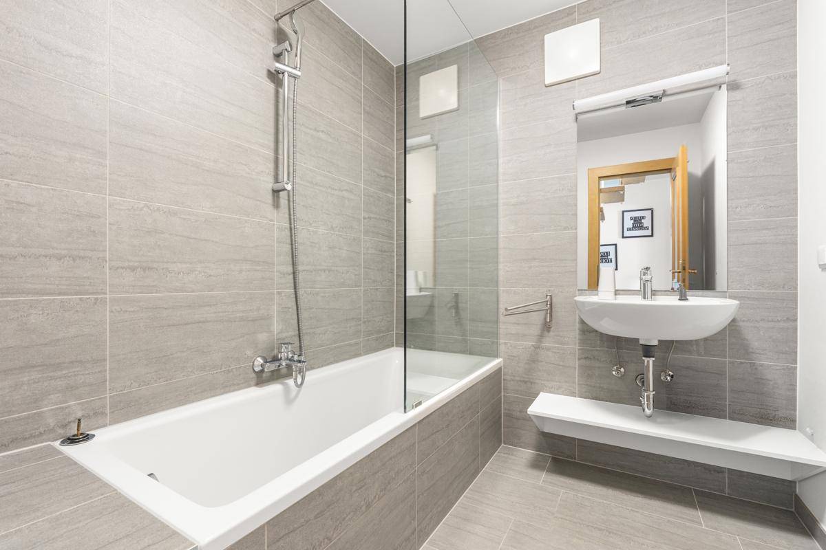 Modernes Badezimmer mit Badewanne, Duschabtrennung und einzelnen Waschbecken.